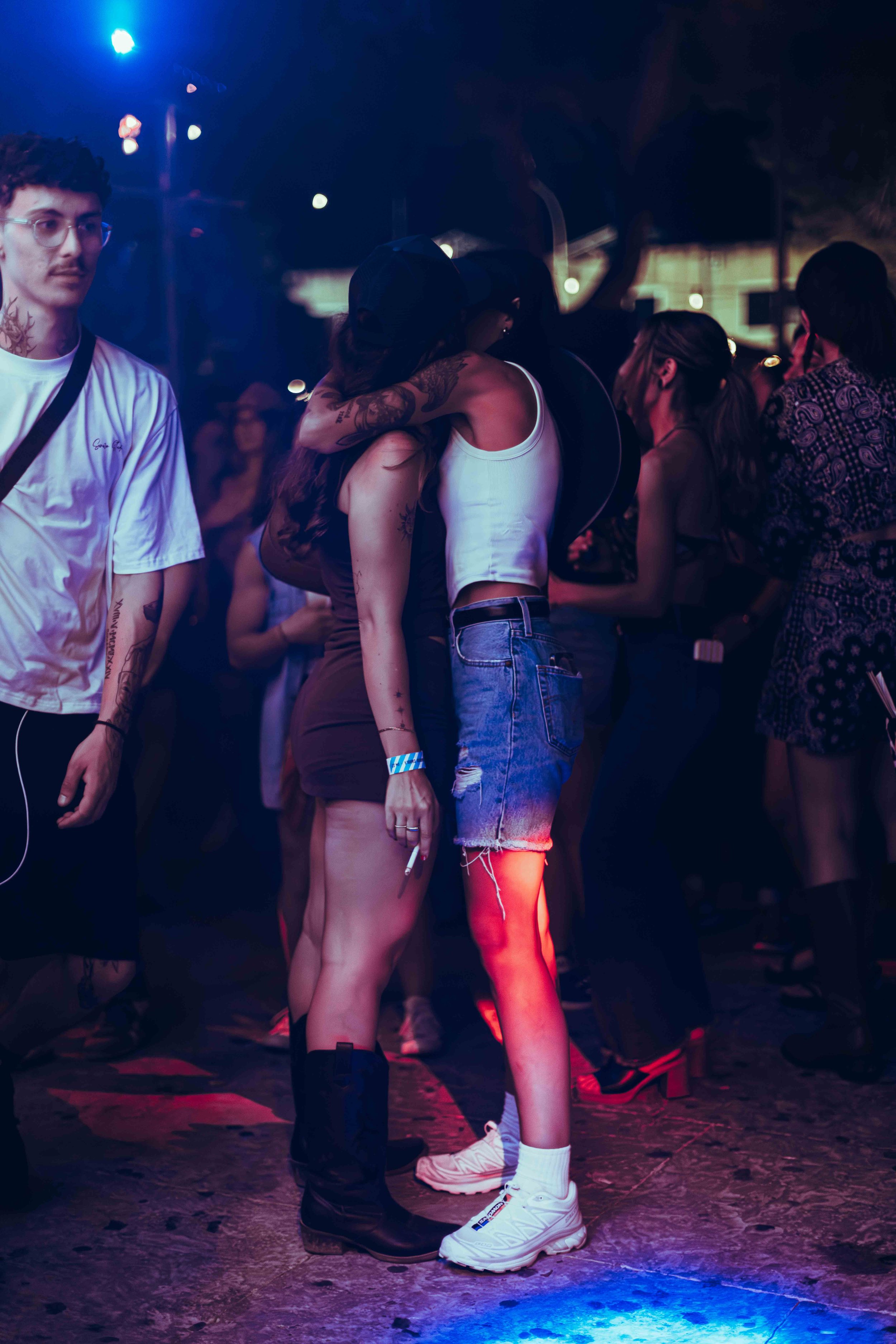 A group of young people dancing at a nightclub with colorful lighting.