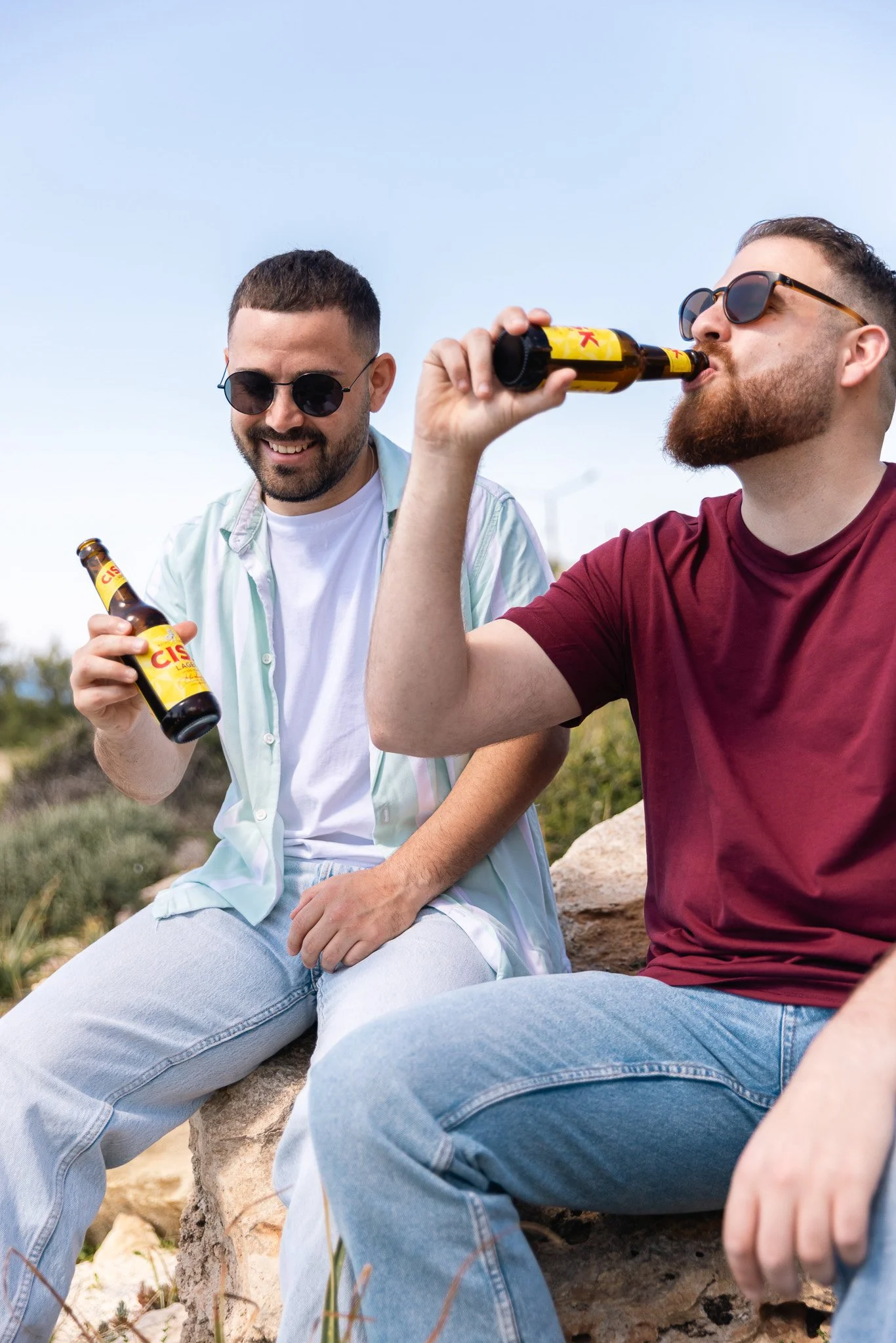 two men having conversation, drinking cisk lager bottle
