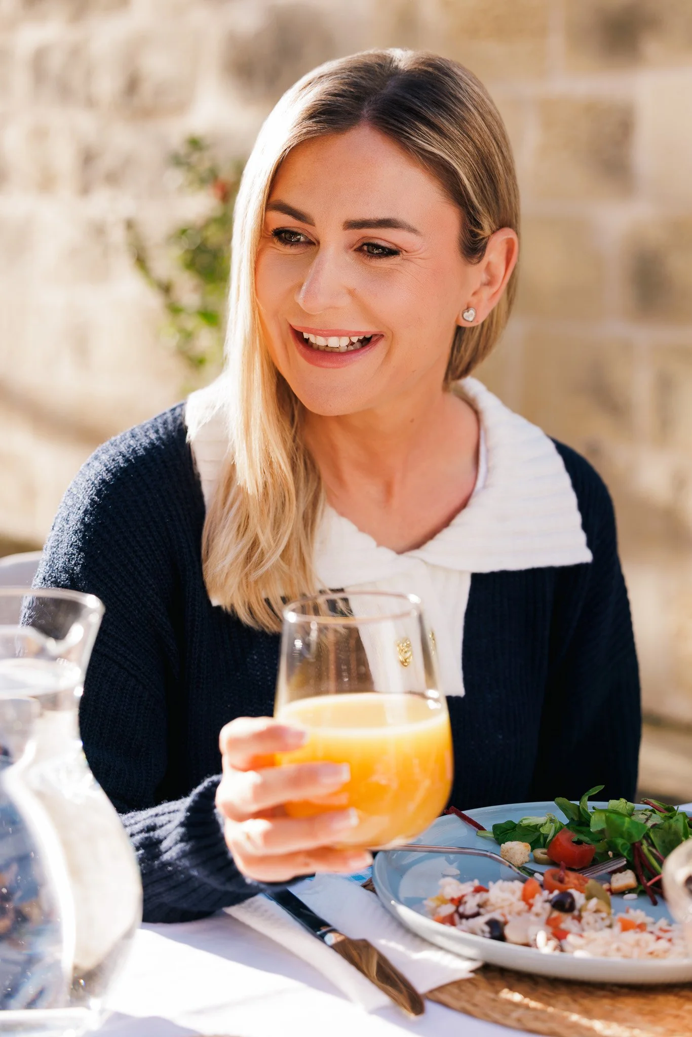 woman smiling and holding a glass of orange juice
