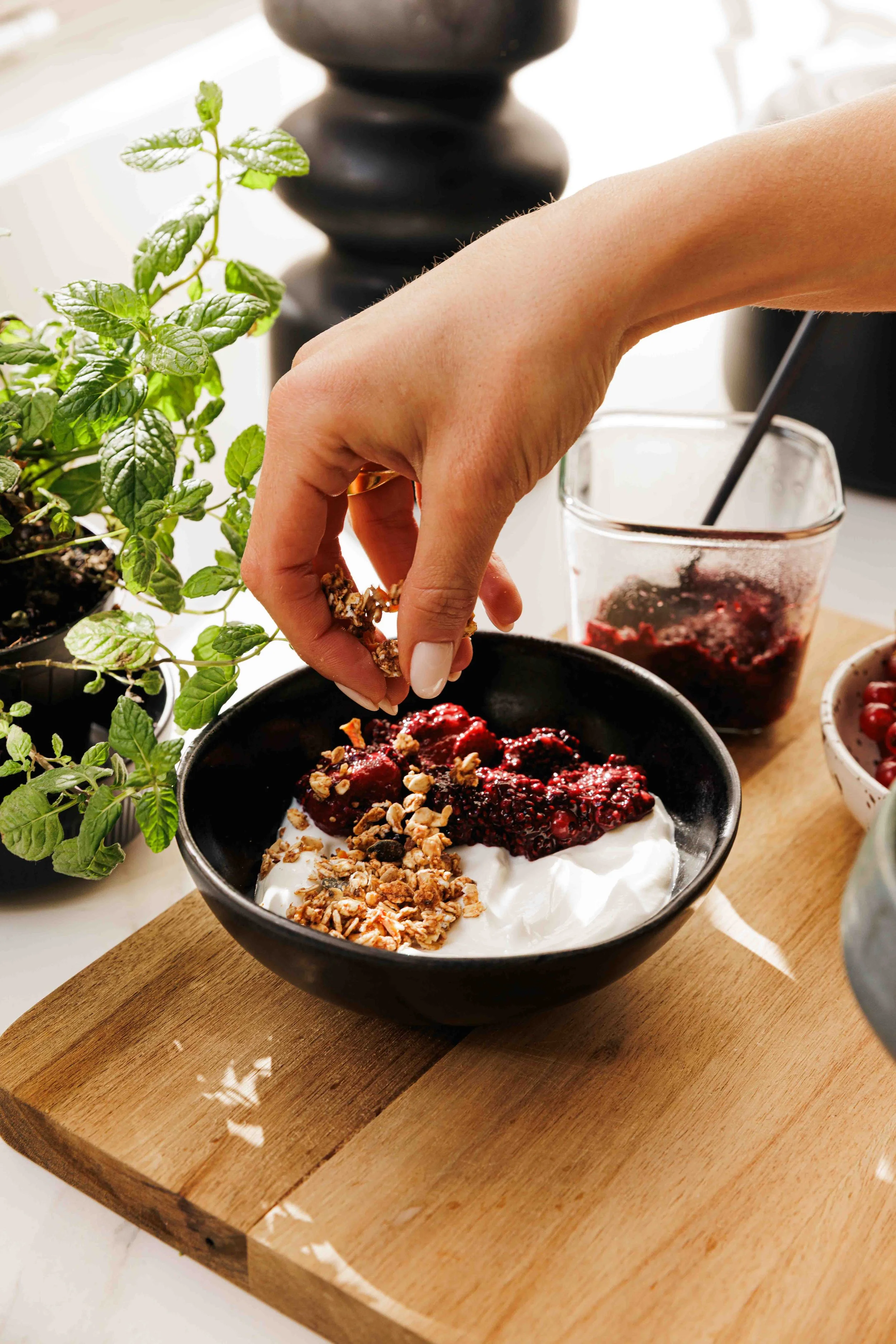 granola being sprinkled into a yoghurt and berries bowl, photoshoot