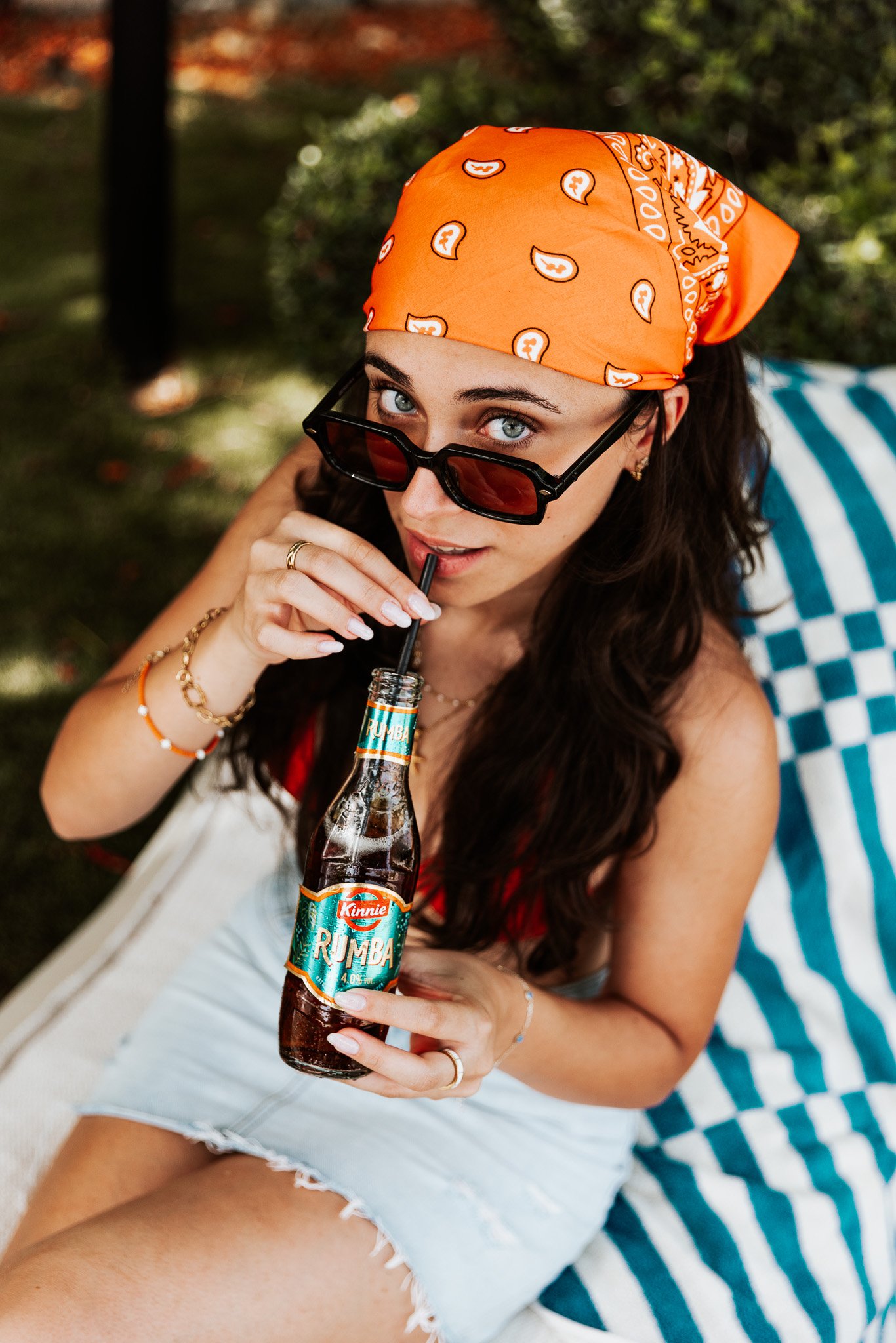 woman with kinnie rumba bottle in hand, top shot looking up to the photographer, summer shoot