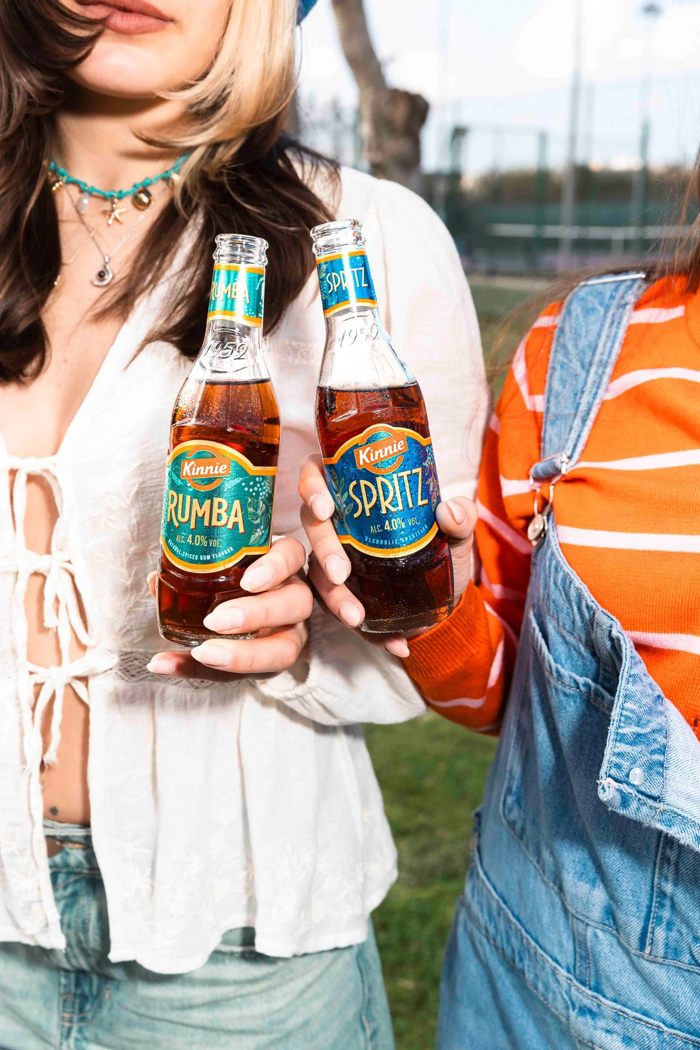women clinking two bottles, kinnie rumba and kinnie spritz, spring time shoot