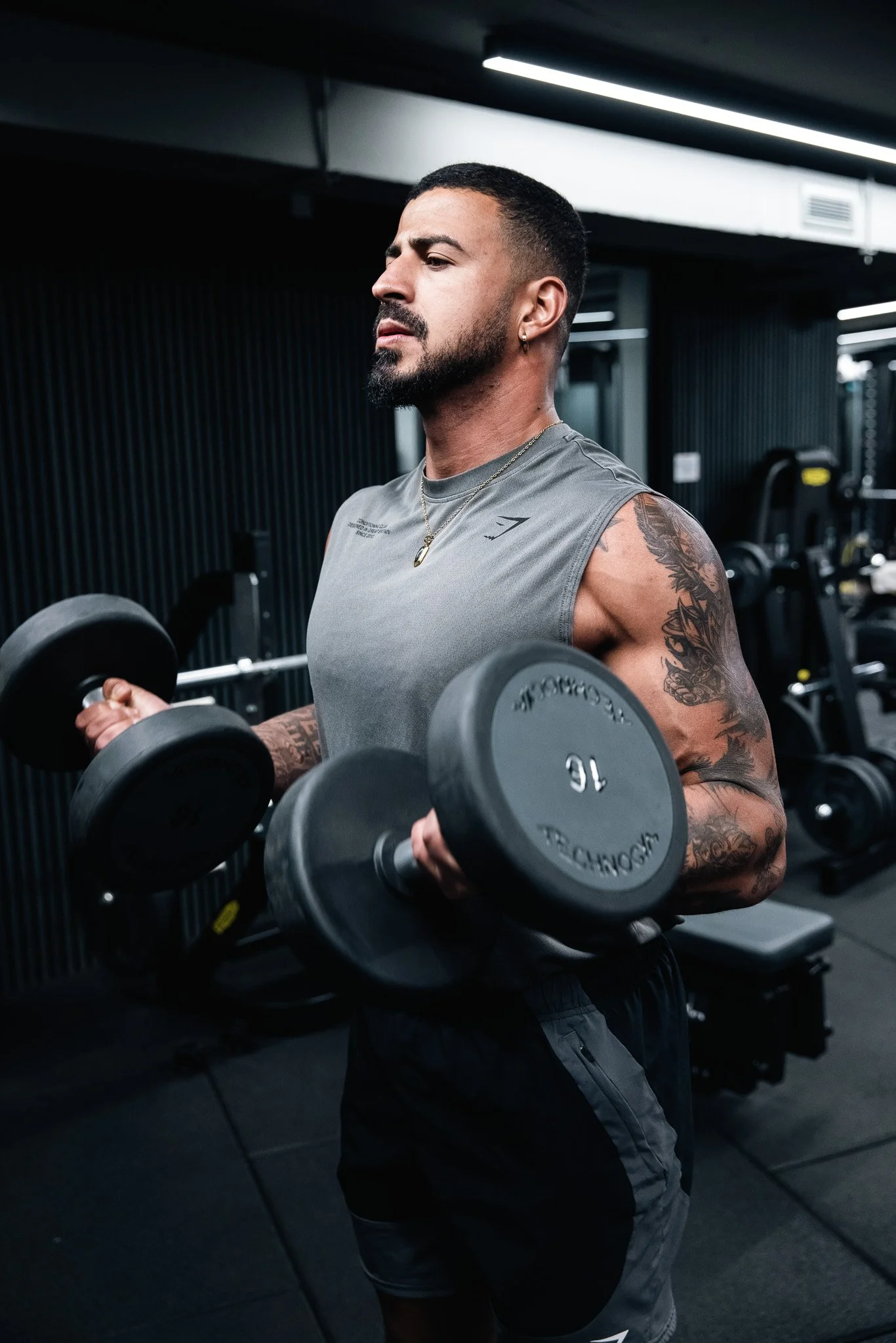 man doing bicep curls with dumbbells, at the gym, trainer