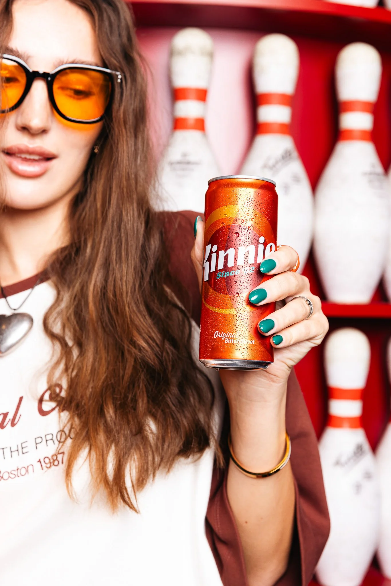 model holding a kinnie can at a bowling alley