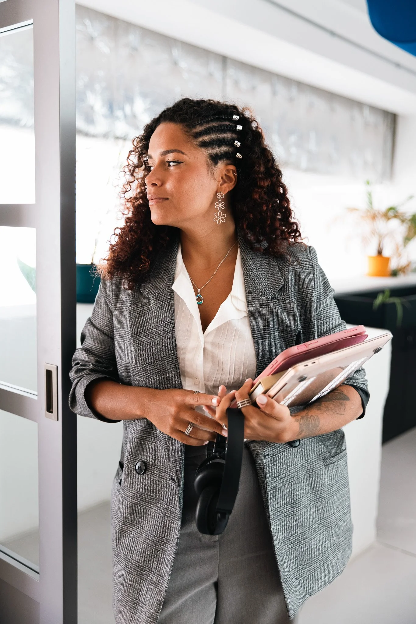 woman in a suit, holding her laptop and notes, at a coworking space, office