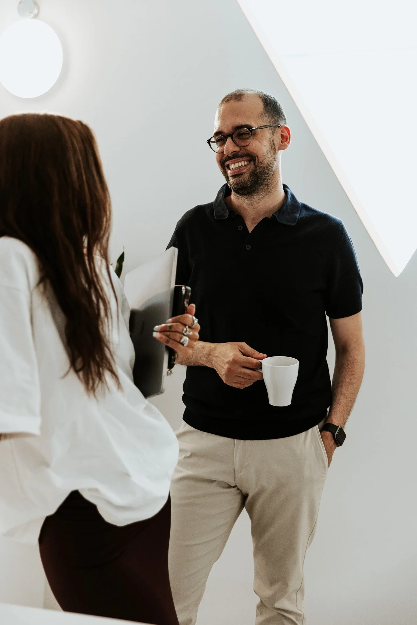 man speaking to a woman with a coffee in his hands