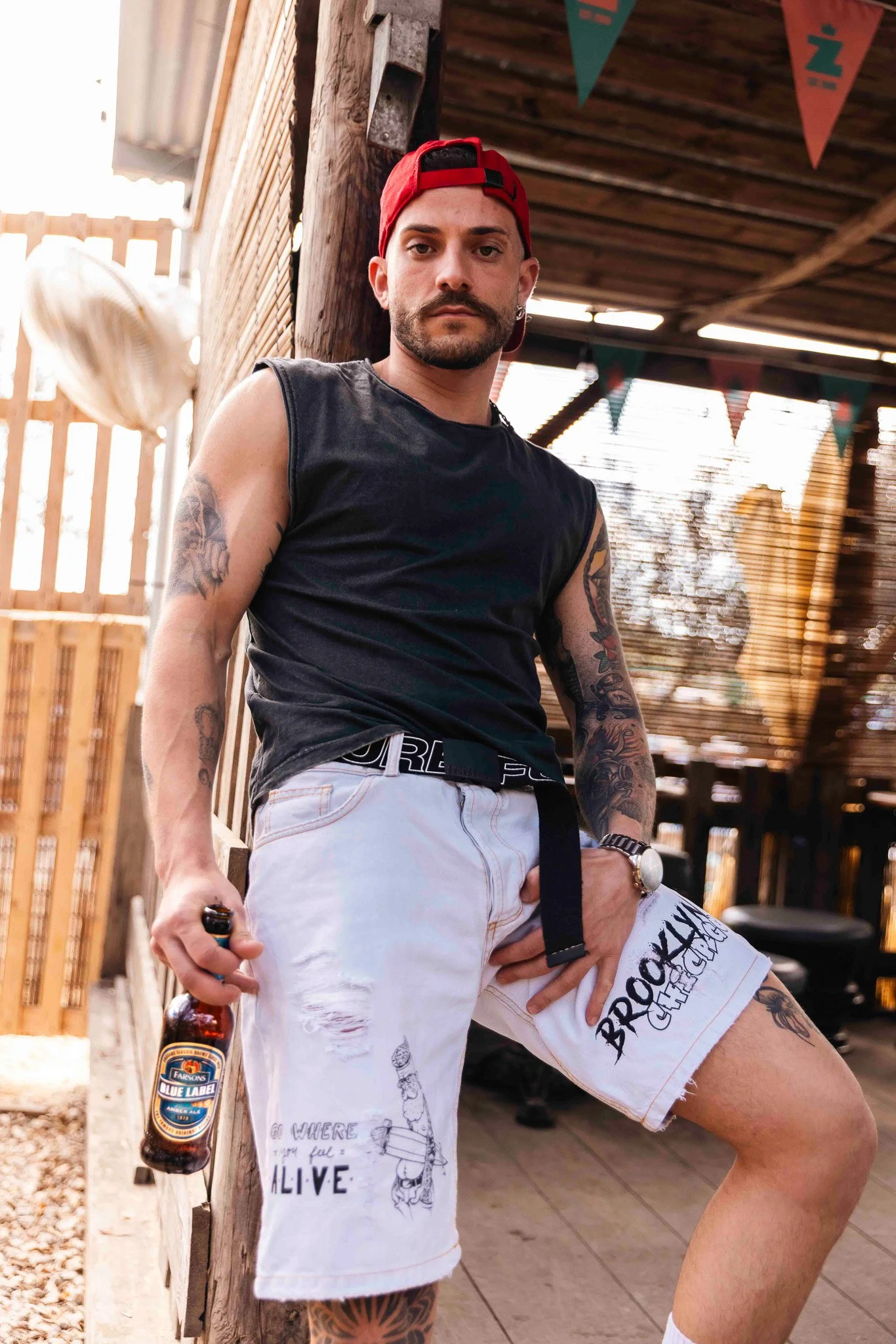cool alternative male model holding a blue label beer bottle, classic brews photoshoot