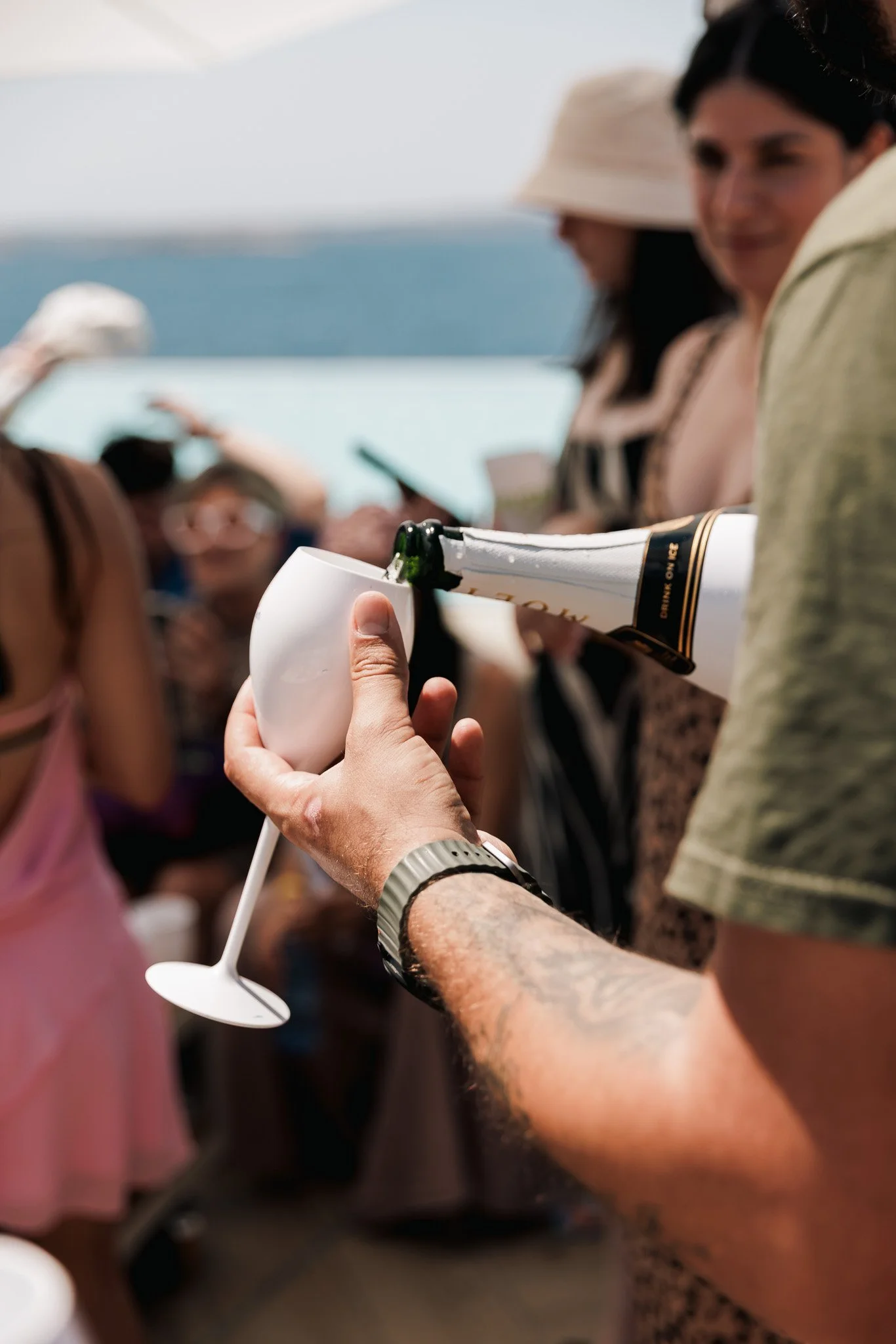 man pouring prosecco in a glass, event photography by the pool.
