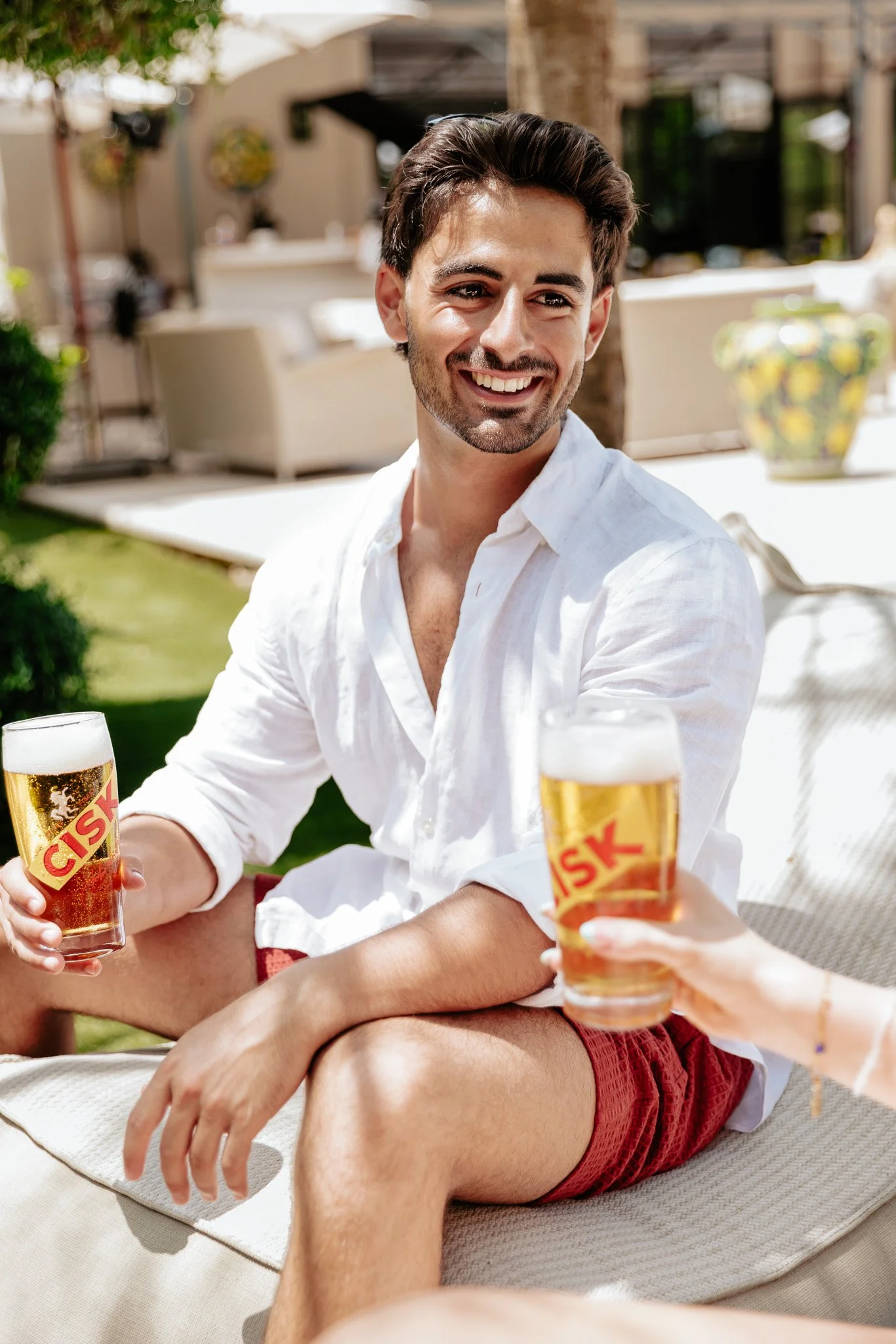 man holding a glass of cisk outdoors, summer shoot