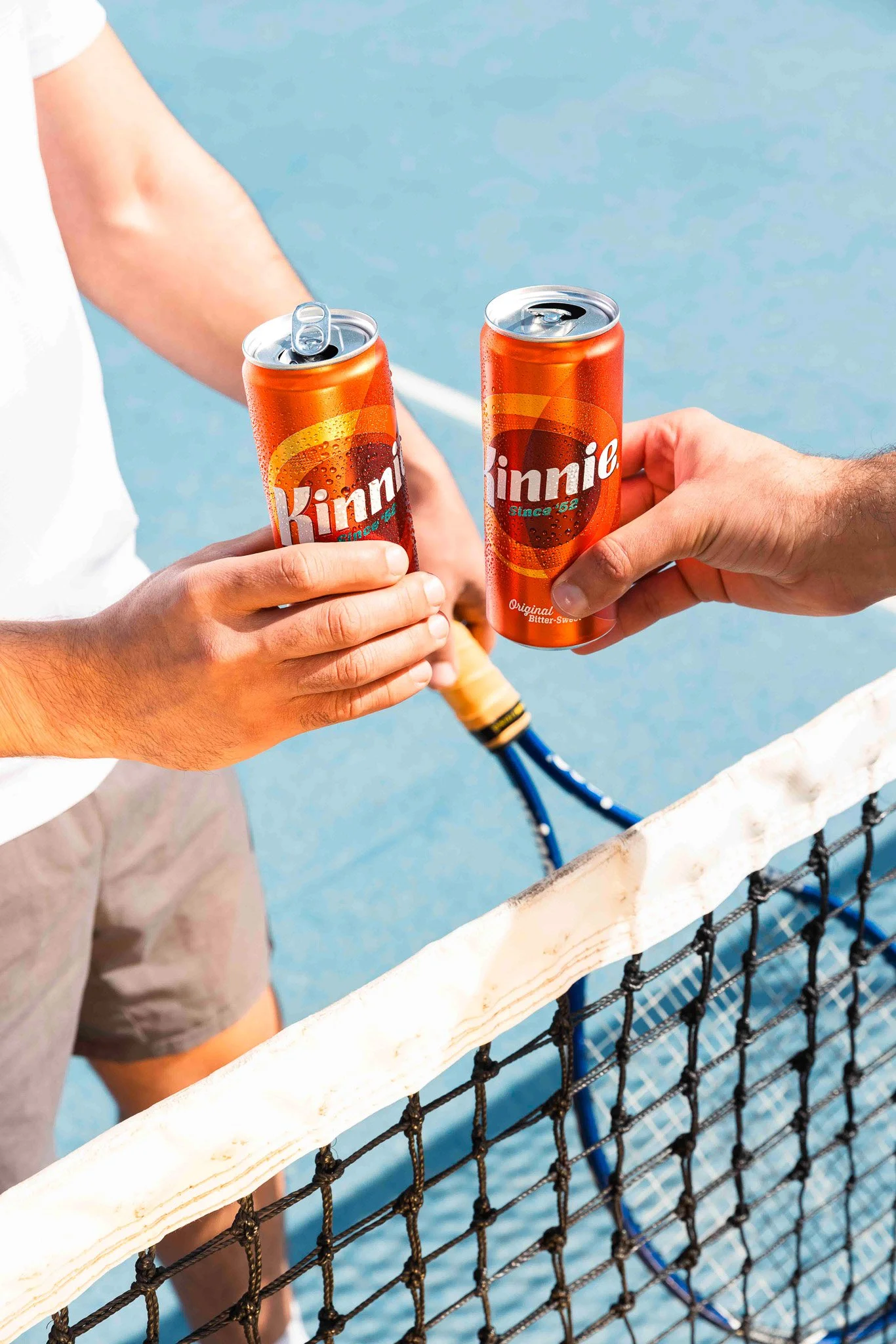 two kinnie cans cheersing at a tennis court