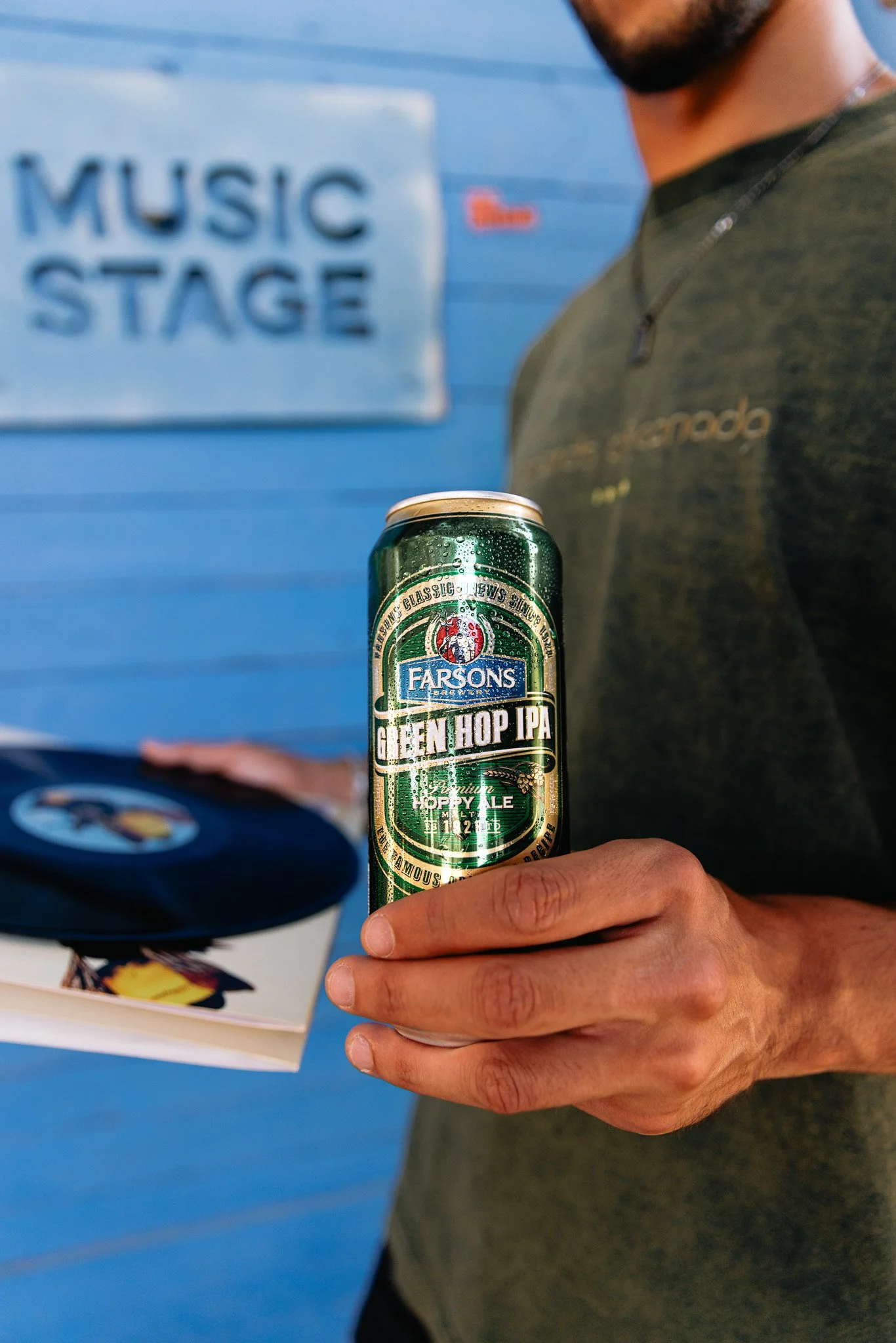 man holding a vinyl and a green hop classic brews can