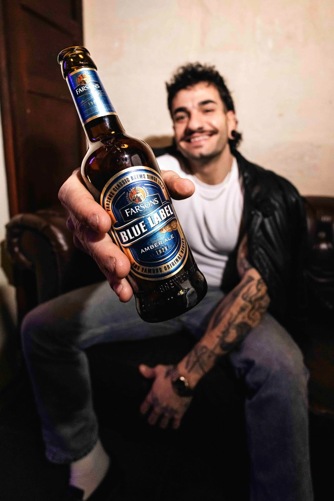 guy holding a blue label classic brews beer bottle, alternative model, photoshoot