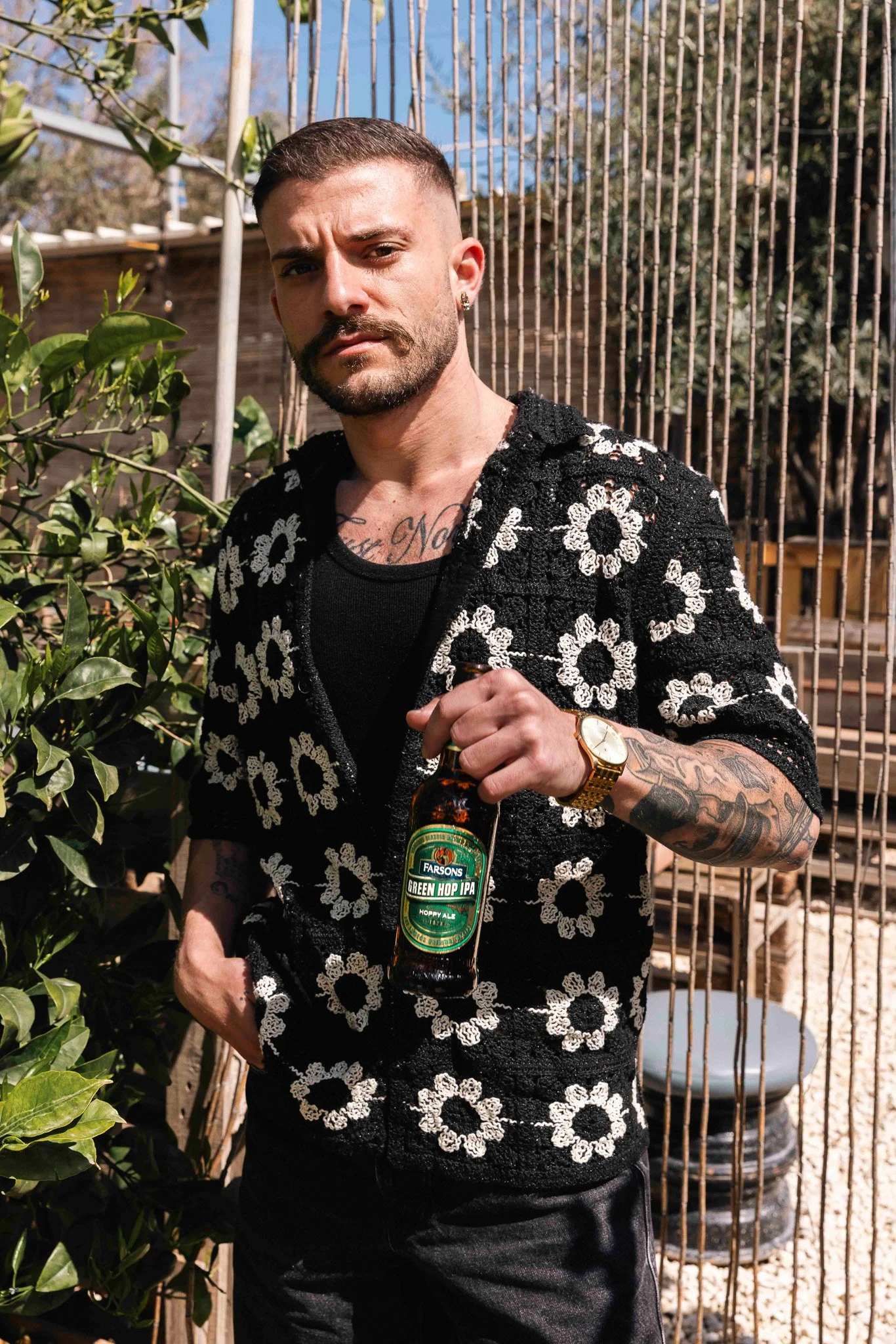 guy with a green hop ipa bottle outdoors, summer time, wearing a flower crocheted shirt, beer