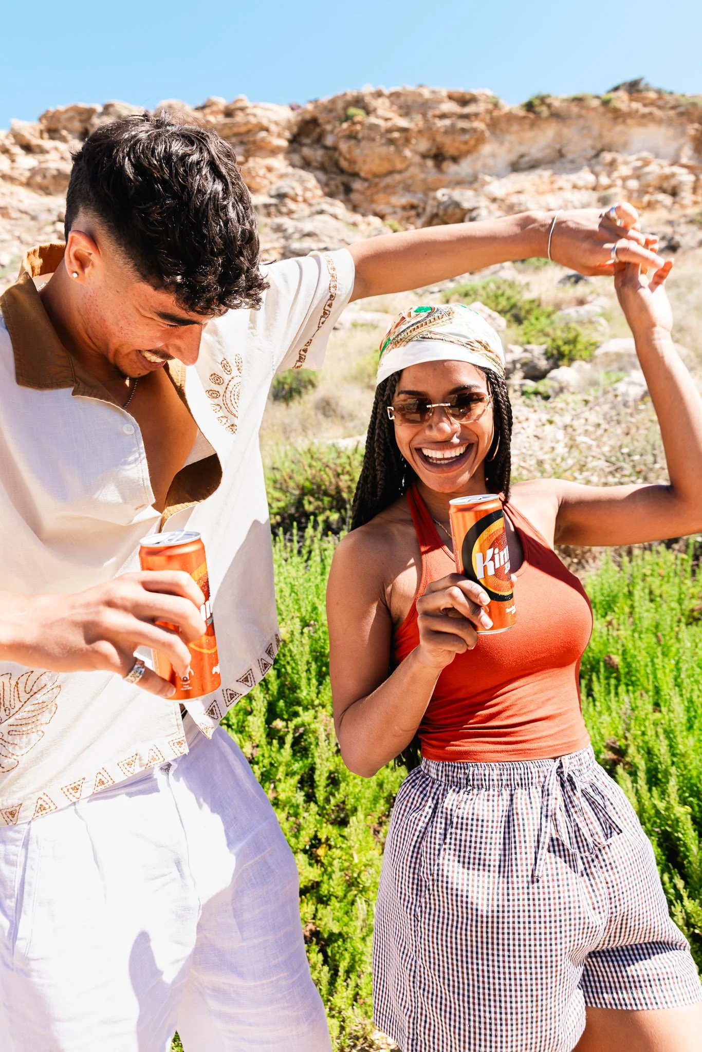two friends dancing with kinnie in hand, outdoors in summer