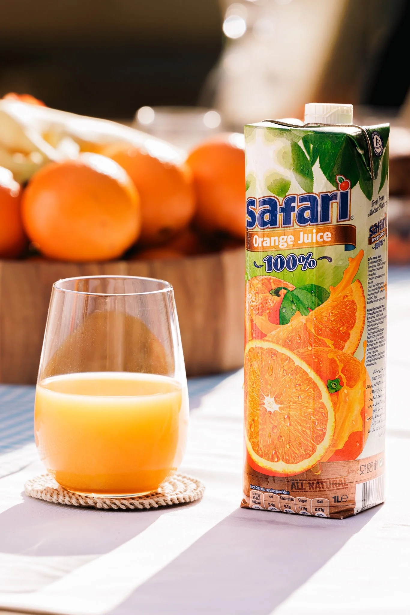 safari juice box, with glass filled with orange juice, on a table, commercial shoot