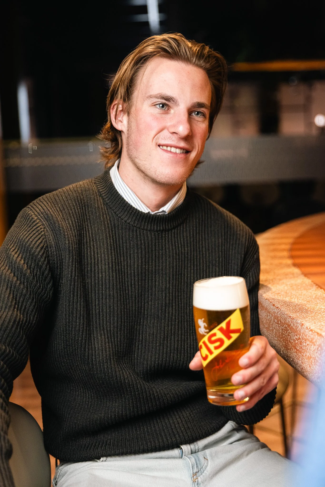 man holding a cisk glass at a bar