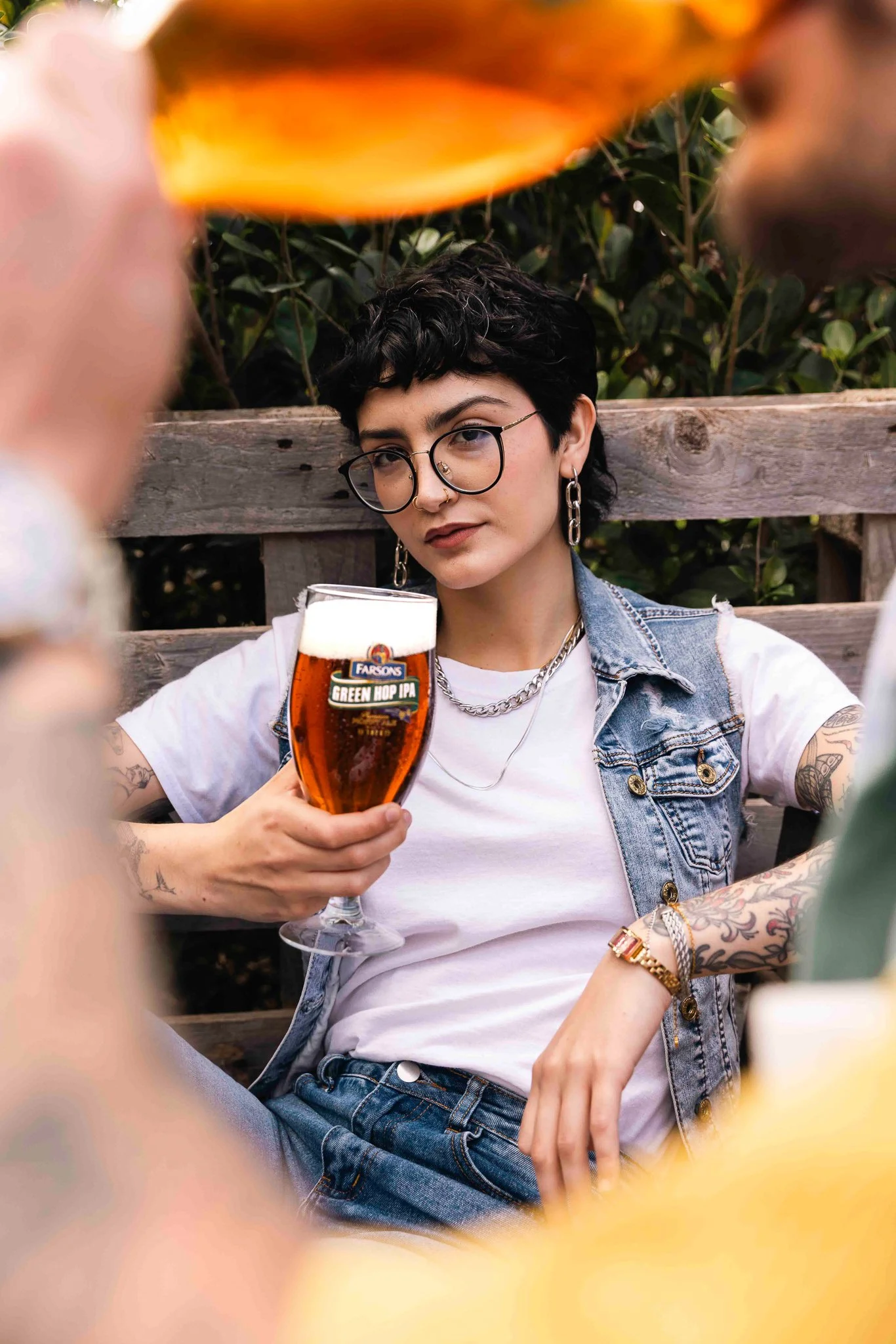 cool alternative female model holding a green hop ipa beer glass, classic brews photoshoot, interesting angle