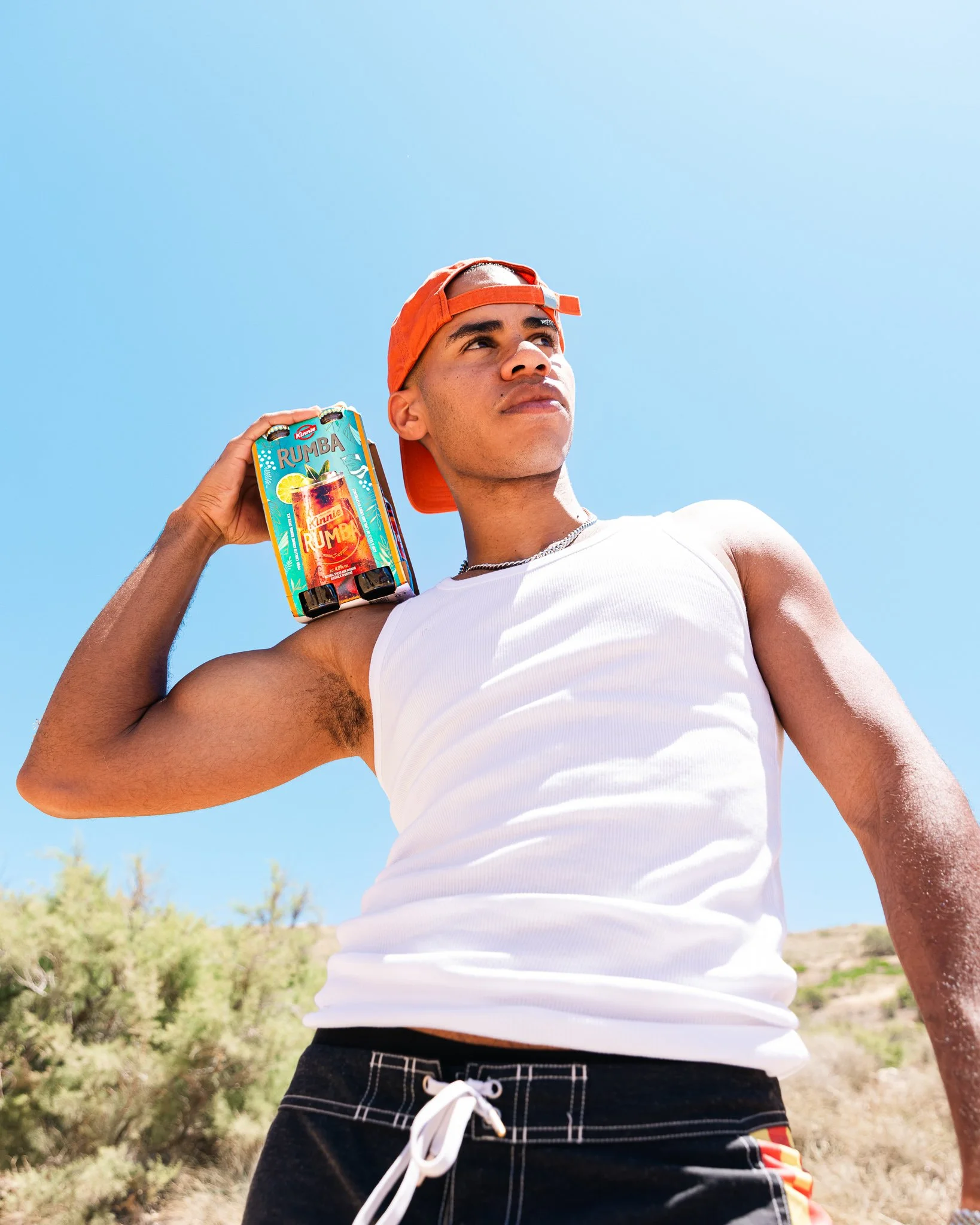guy holding a pack of kinnie rumba outdoors, cool pose, summer photoshoot