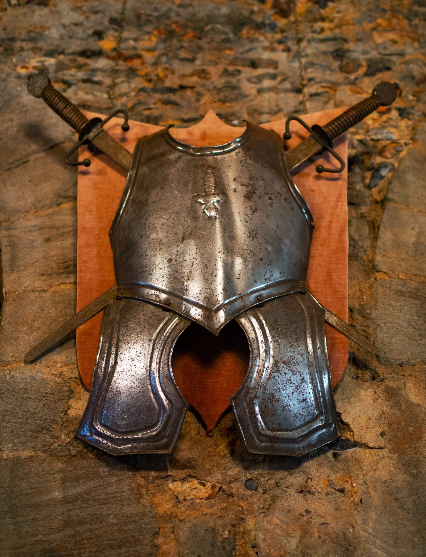 Medieval breastplate and two swords displayed on a wall
