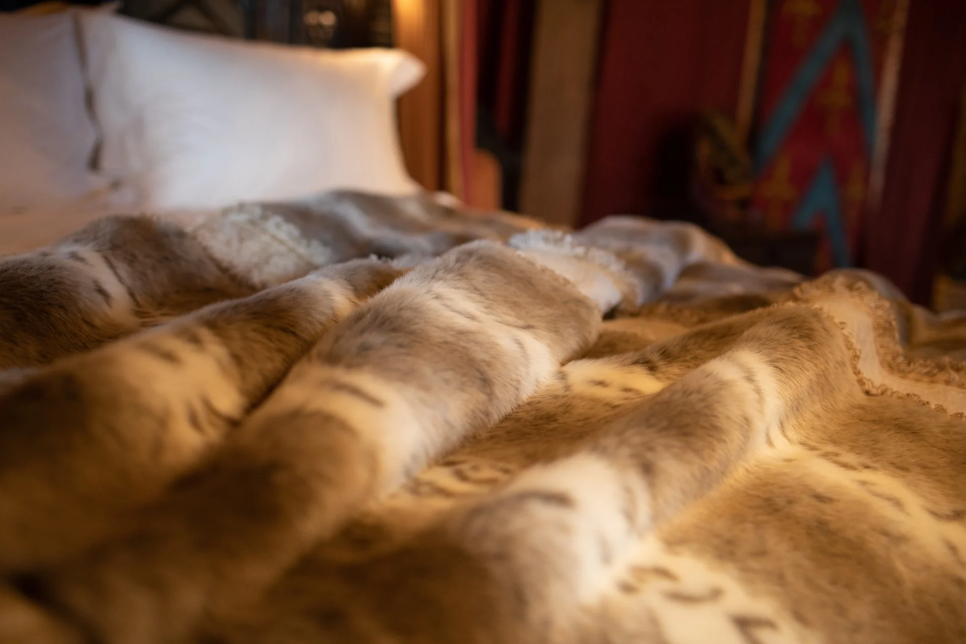 Soft fur blanket on a bed with white pillows in a cozy bedroom setting.
