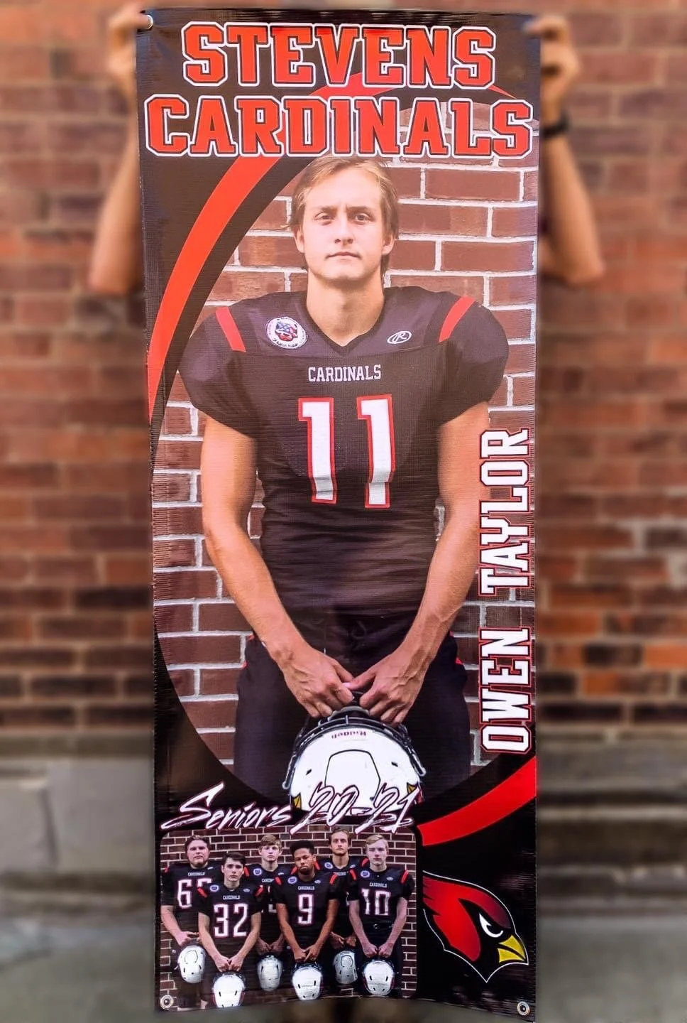 Vertical banner featuring a young football player in a black and red uniform with number 11, standing against a brick wall. The banner includes text "STEVENS CARDINALS," "OWEN TAYLOR," and "Seniors 2022". A smaller photo at the bottom shows five foot