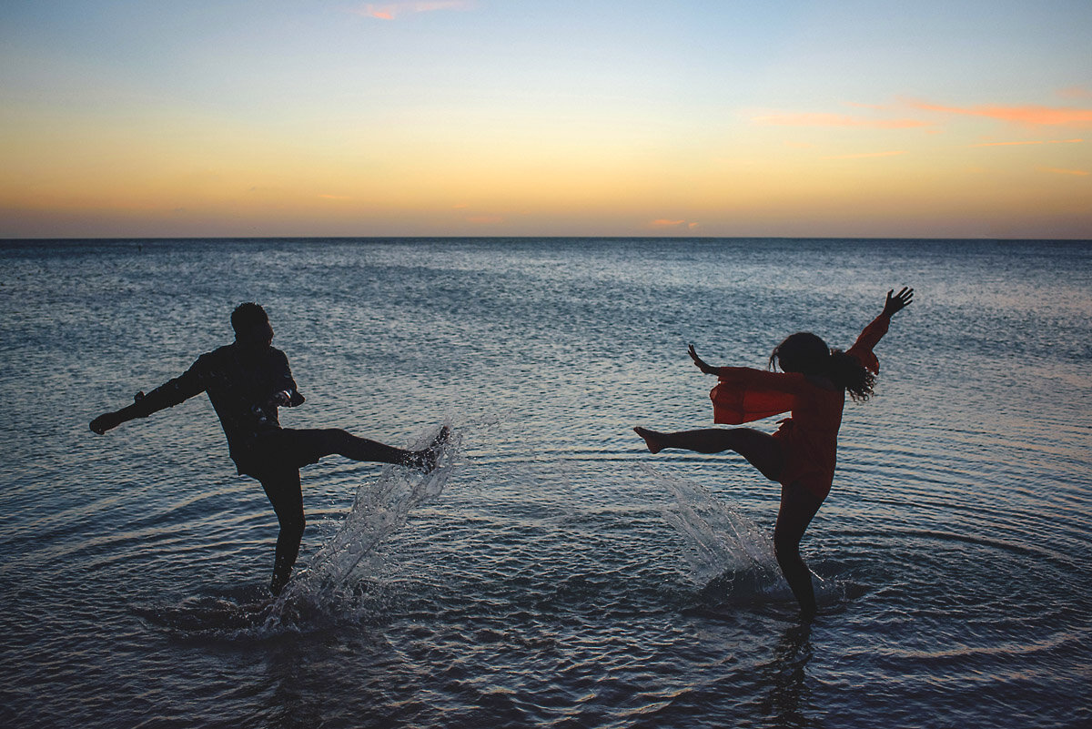 04-Aruba-wedding-photographer-Jide-Alakija-Couple kicking water on beach towards each other in aruba- engagment shoot.jpg.JPG