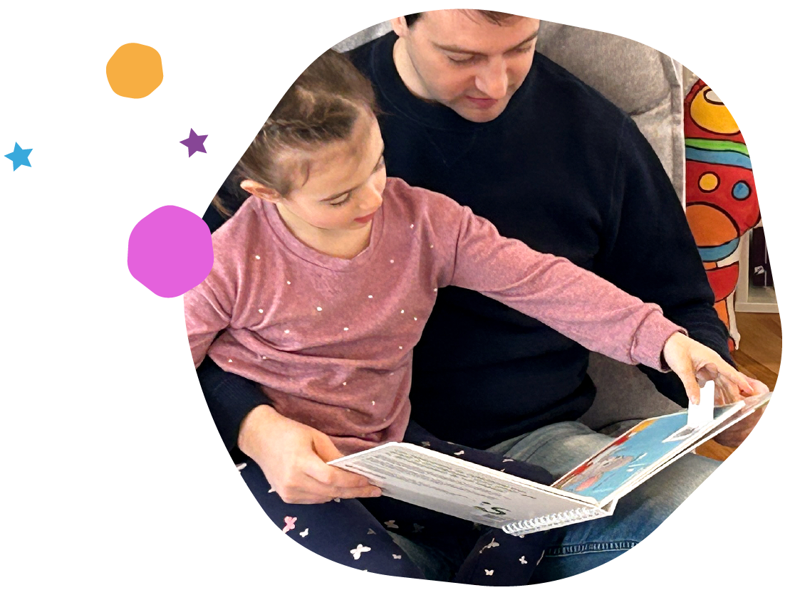 Une jeune fille et un homme assis sur un canapé, regardant un livre.