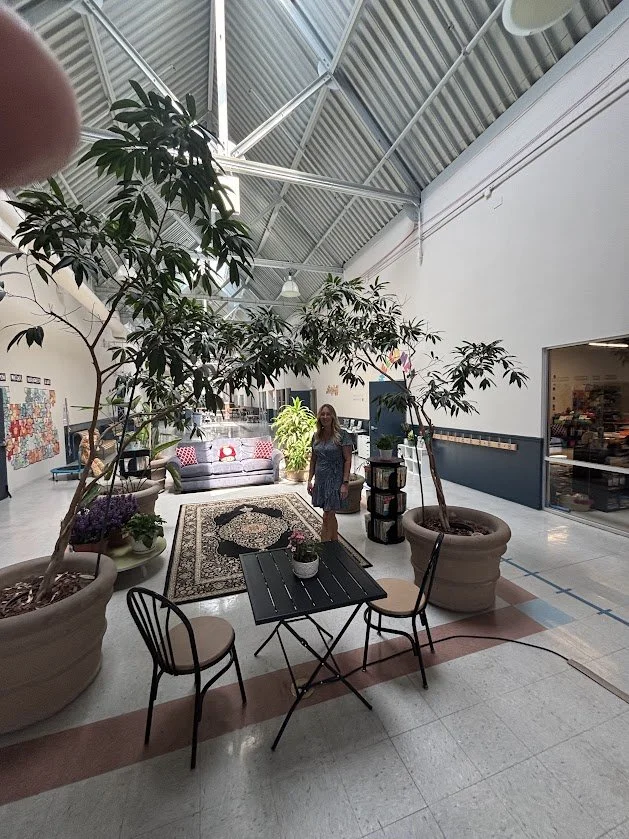 The open common area at the Lumos campus, with high ceilings, trees, and seating