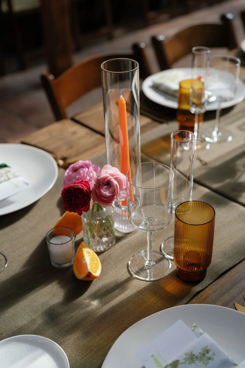 Decorated dining table with flowers, candles, lemon slices, and glassware in warm lighting.
