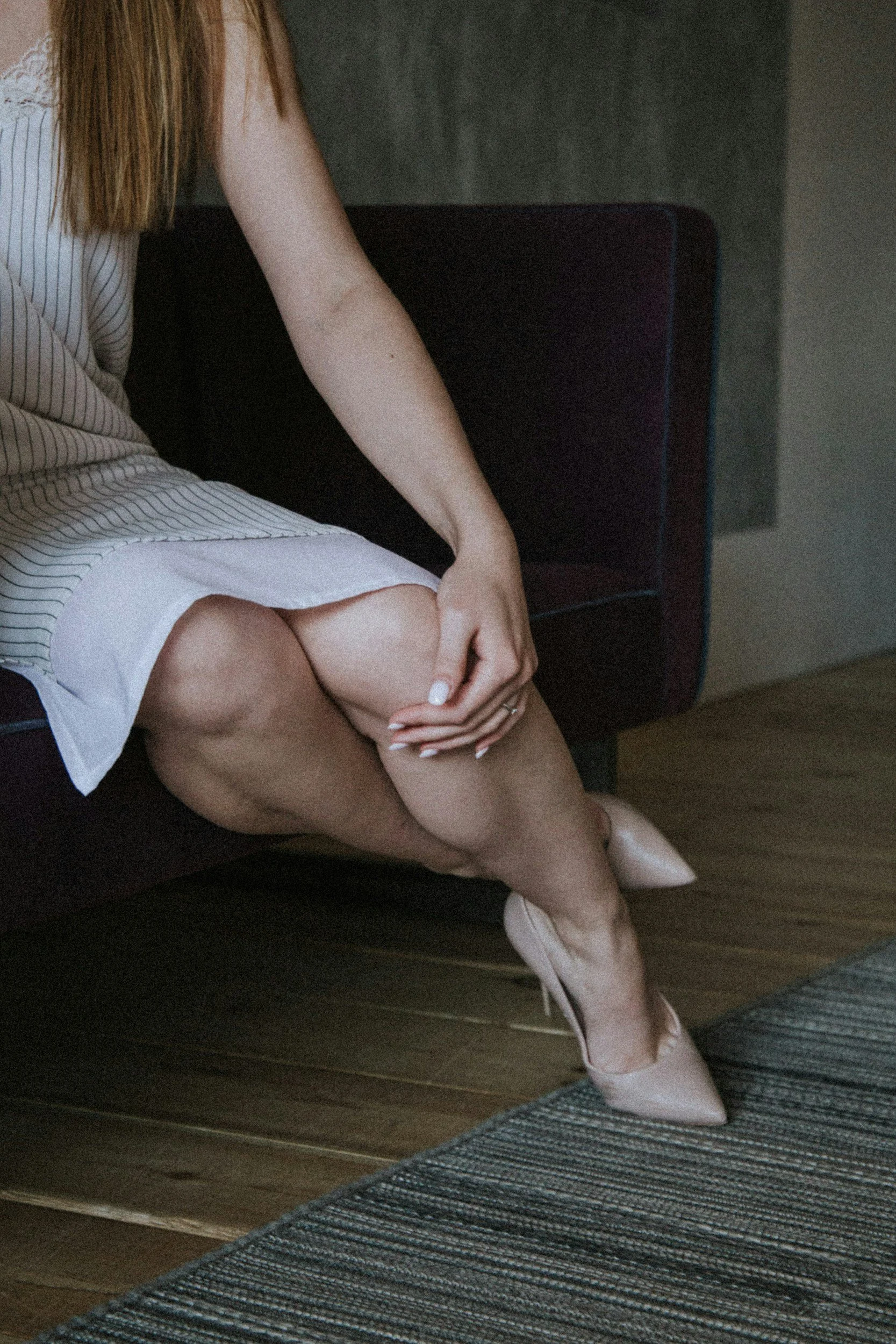 a woman sitting on the end of a bed in heels