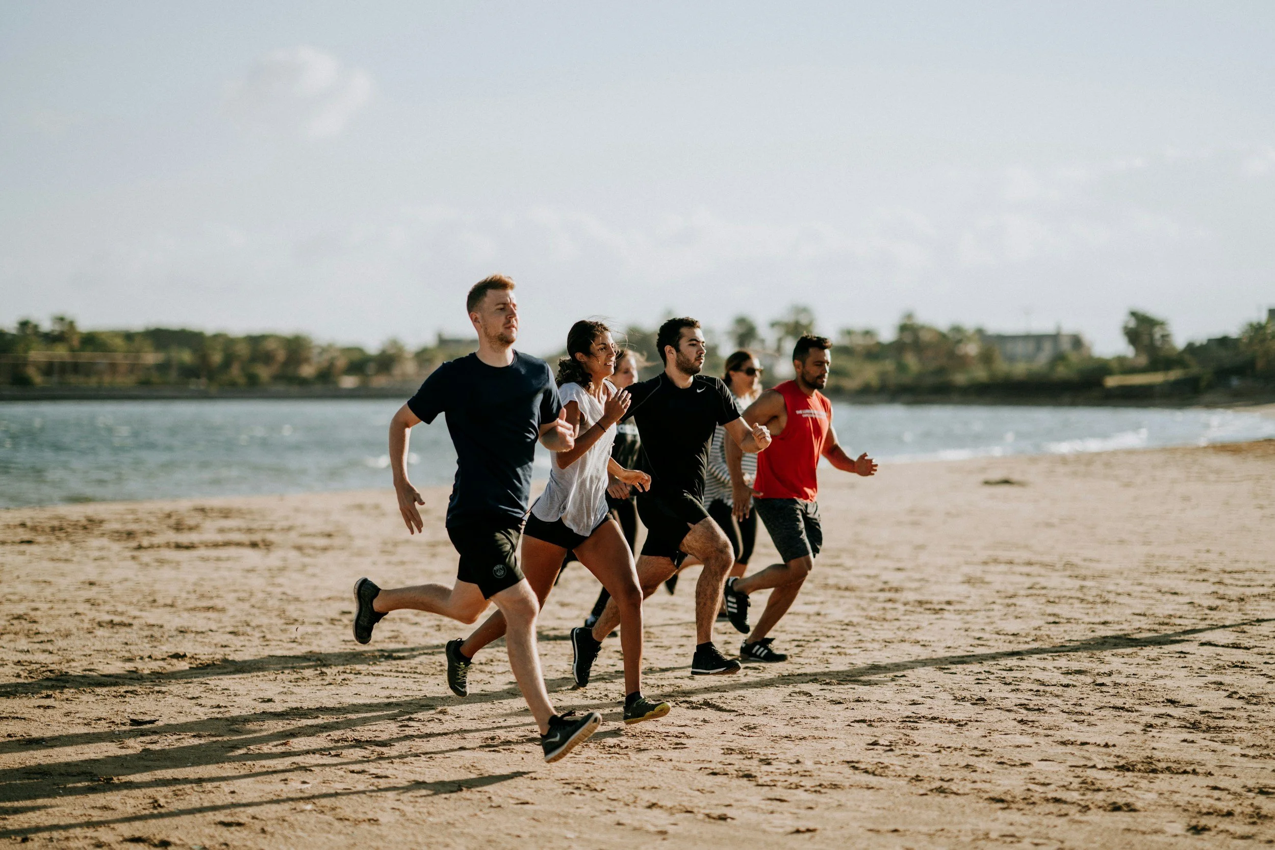 a group of people running on the beach