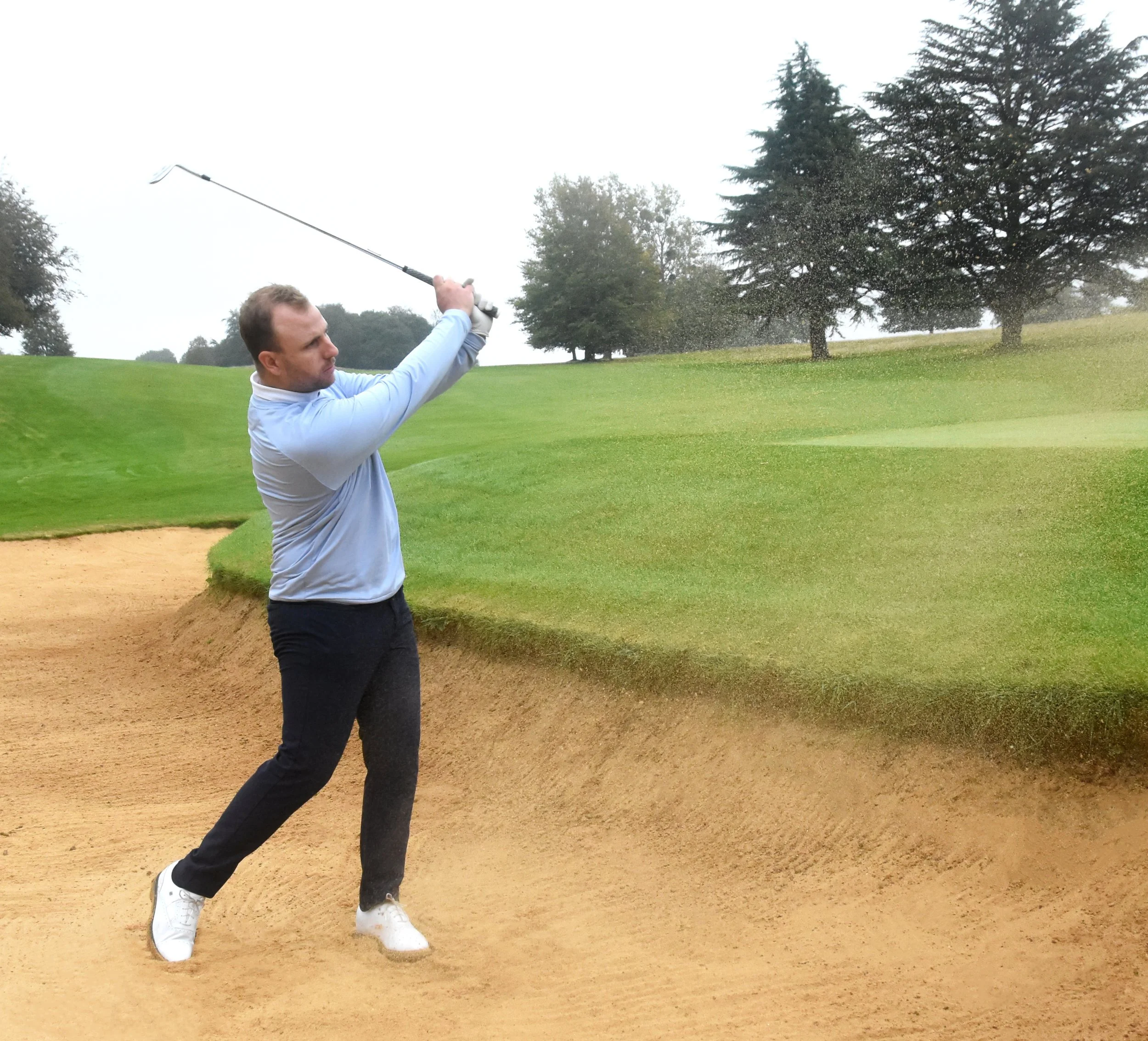 Golfer hitting shot from sand bunker on a golf course