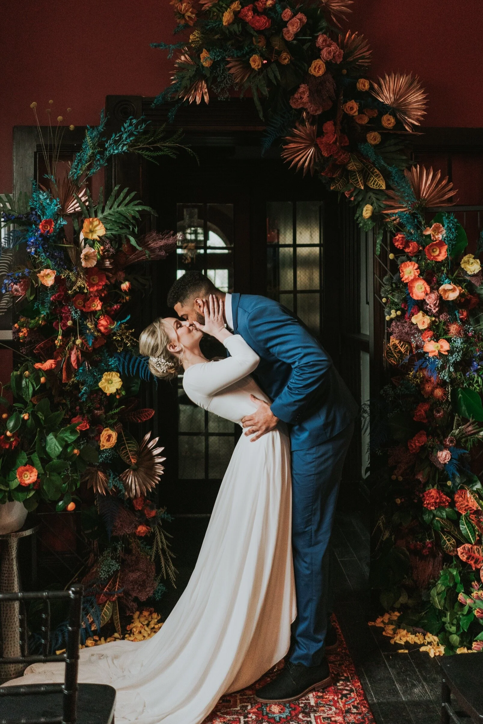 couple kissing on their wedding day under a dramatic wedding arch