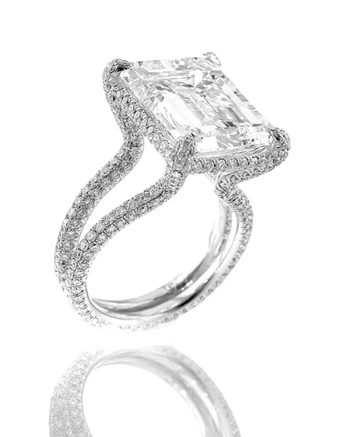 A silver ring with a large rectangular gemstone and smaller diamonds set around it and along the band.