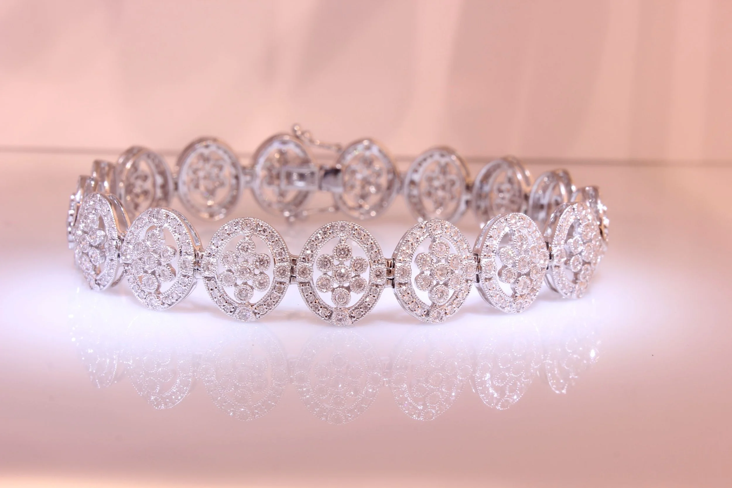 A silver bracelet decorated with numerous small, sparkling diamonds arranged in an intricate pattern.