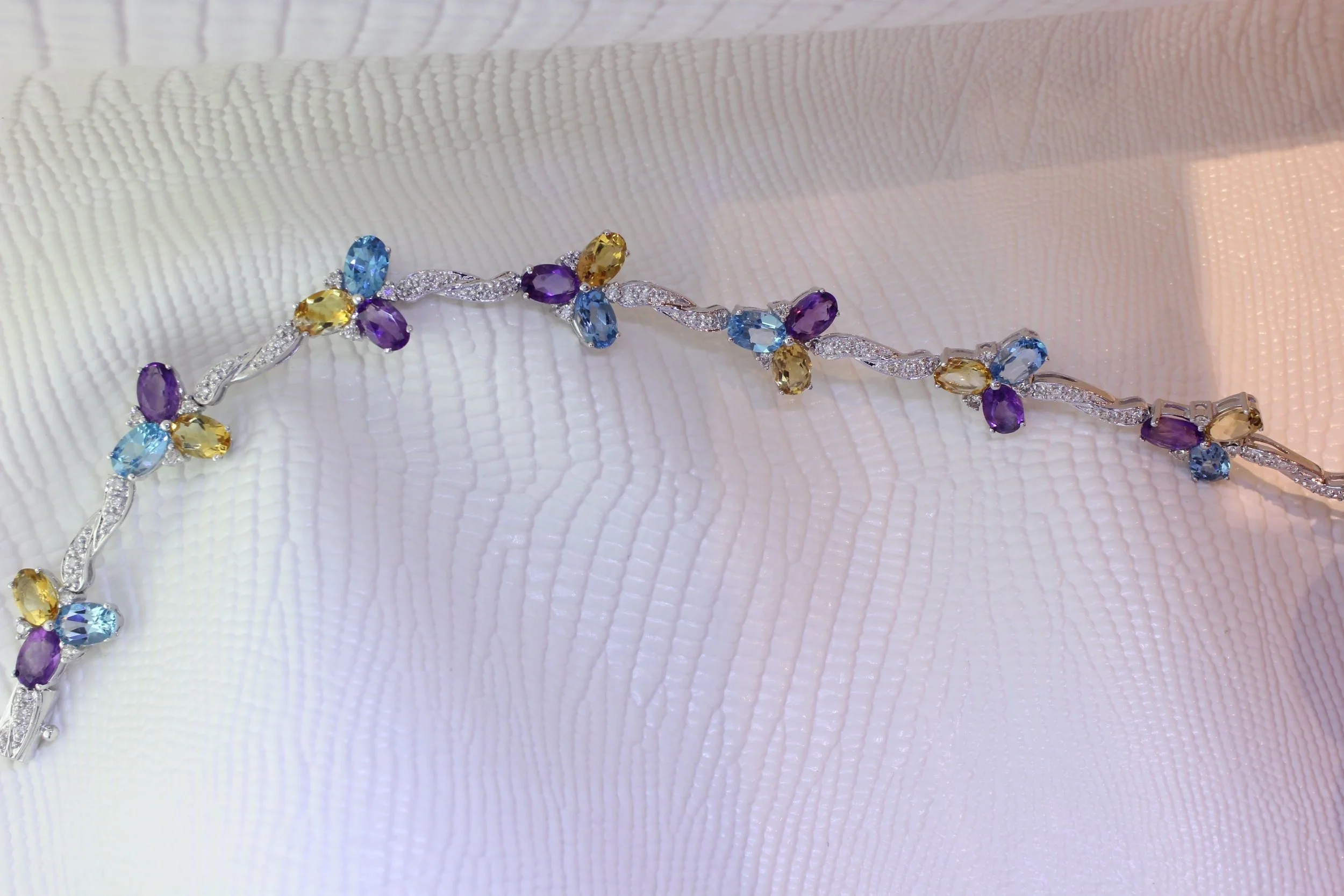 A colorful gemstone bracelet resting on a textured white surface.