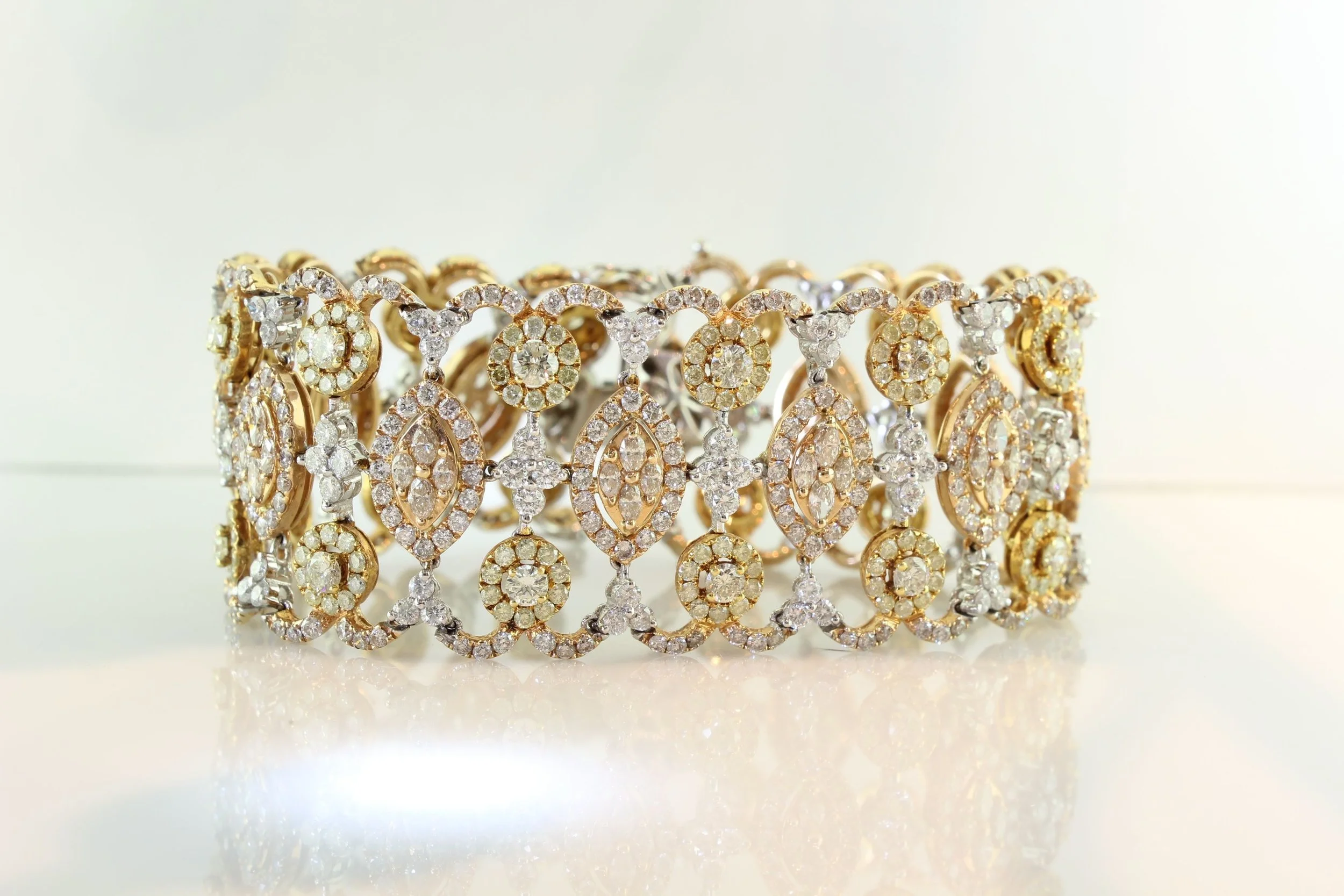 A luxurious gold and silver bracelet adorned with numerous sparkling gemstones, arranged in intricate symmetrical patterns, reflecting light.