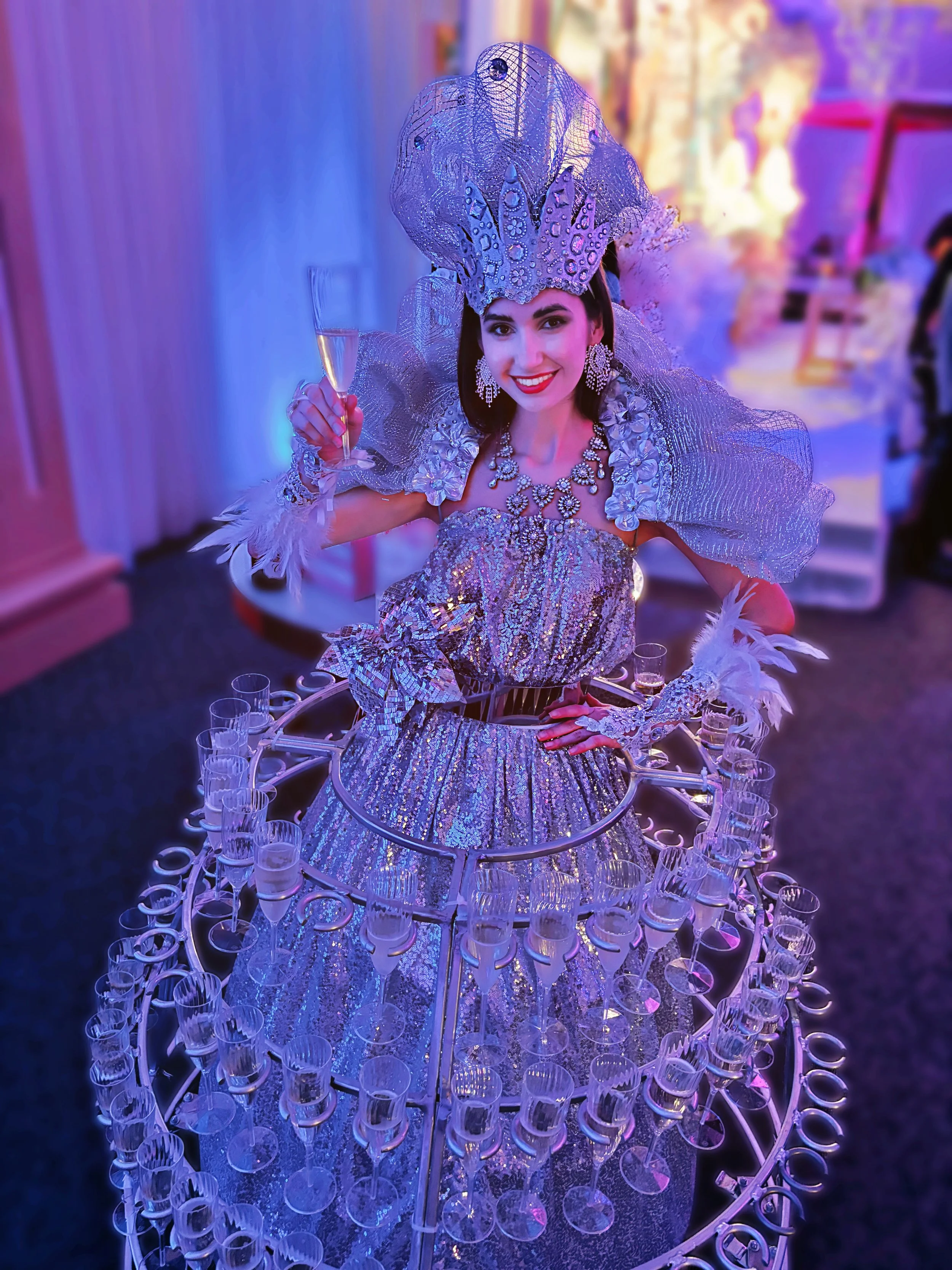 Woman in an elaborate silver dress with champagne glasses