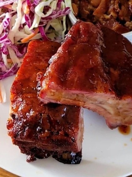Barbecued ribs with coleslaw, baked beans, on a white plate