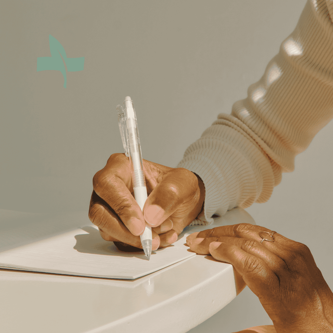Close-up of hands writing in a journal, representing symptom journaling as a tool for chronic condition management.