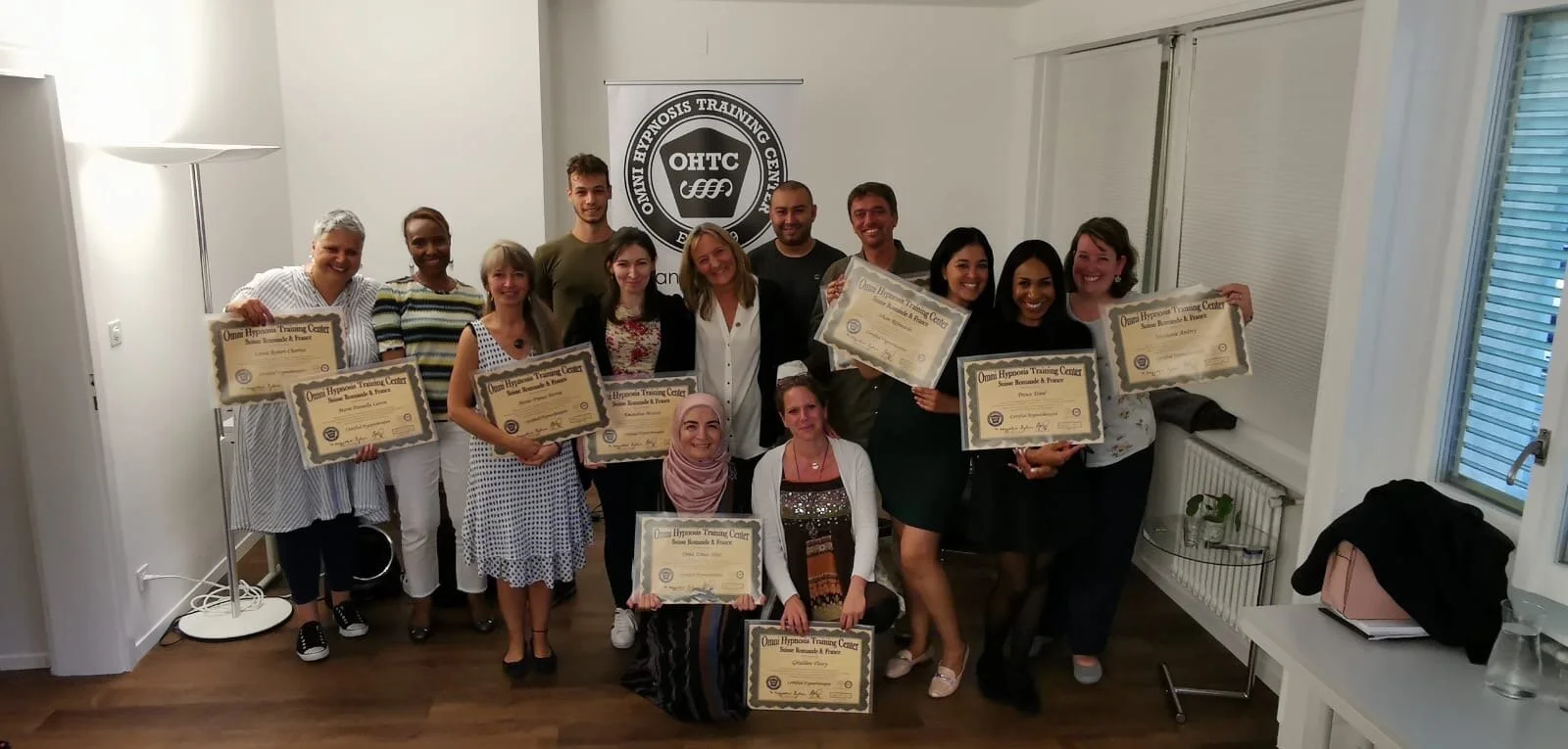 Groupe de personnes posant avec des certificats lors d'une cérémonie de remise à un centre de formation en hypnose.