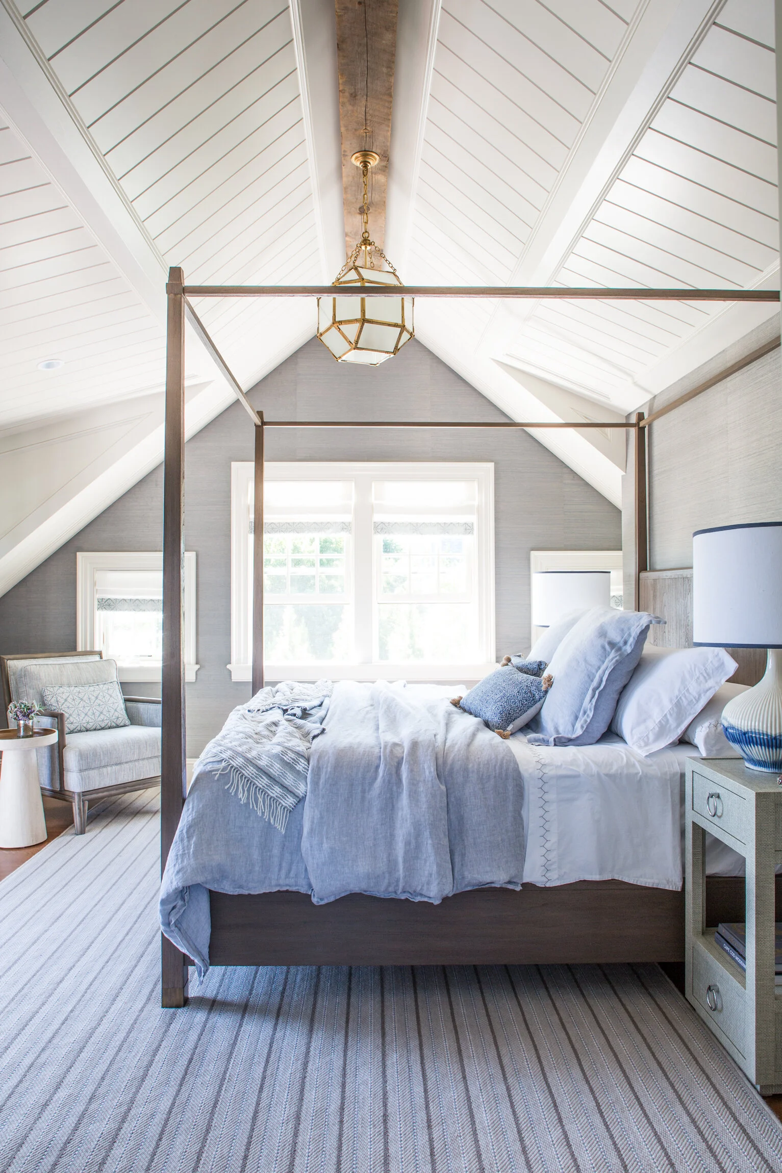 Bright bedroom with a canopy bed, silver lamps, a gray and white color scheme, and a striped carpet.