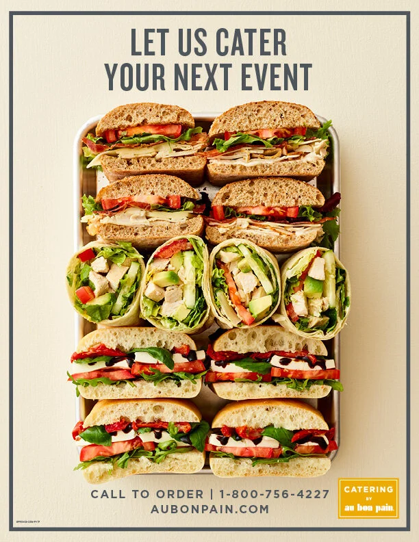 A catering advertisement featuring various sandwiches on a tray, including turkey, vegetable wraps, and BLT, with text "Let us cater your next event" and contact information. In-Store poster for Au Bon Pain Cafe