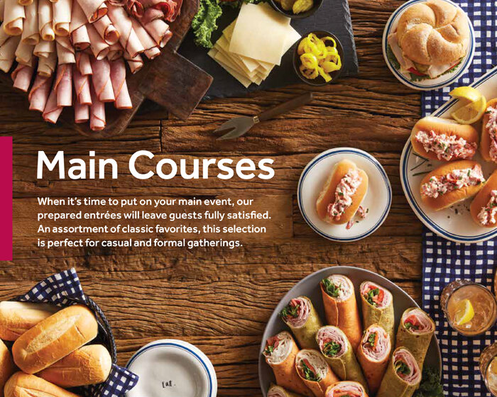 Assorted sandwiches, wraps, and cold cuts on a wooden table, with some plates and napkins, for a buffet or party setting. A page from Sop n Shop's catering brochure.