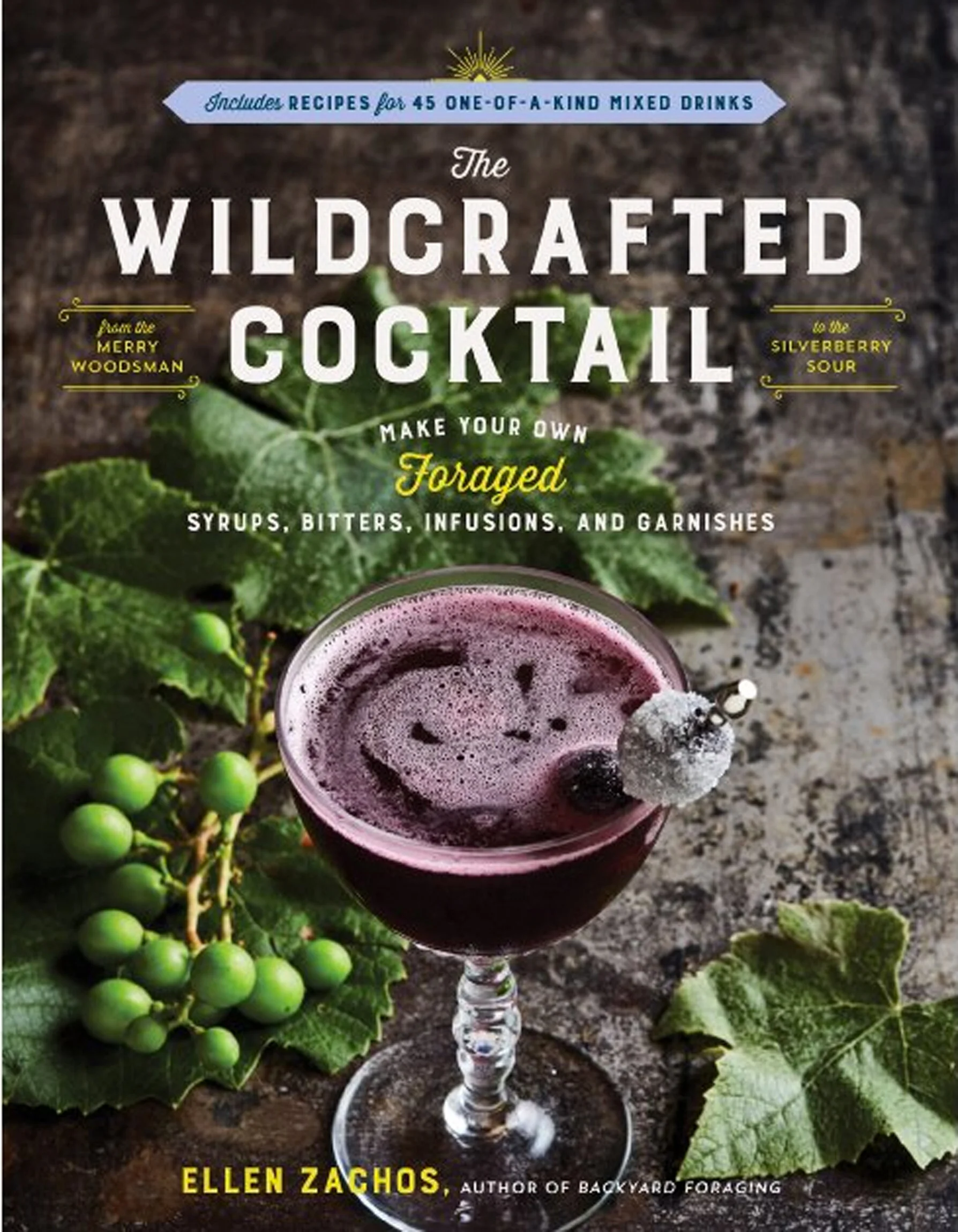 Cover of a cocktail recipe book titled "The Wildcrafted Cocktail" by Ellen Zachos, featuring a glass of purple mixed cocktail garnished with a sugared blackberry and a sprig of greenery, surrounded by green leaves and berries on a rustic surface.
