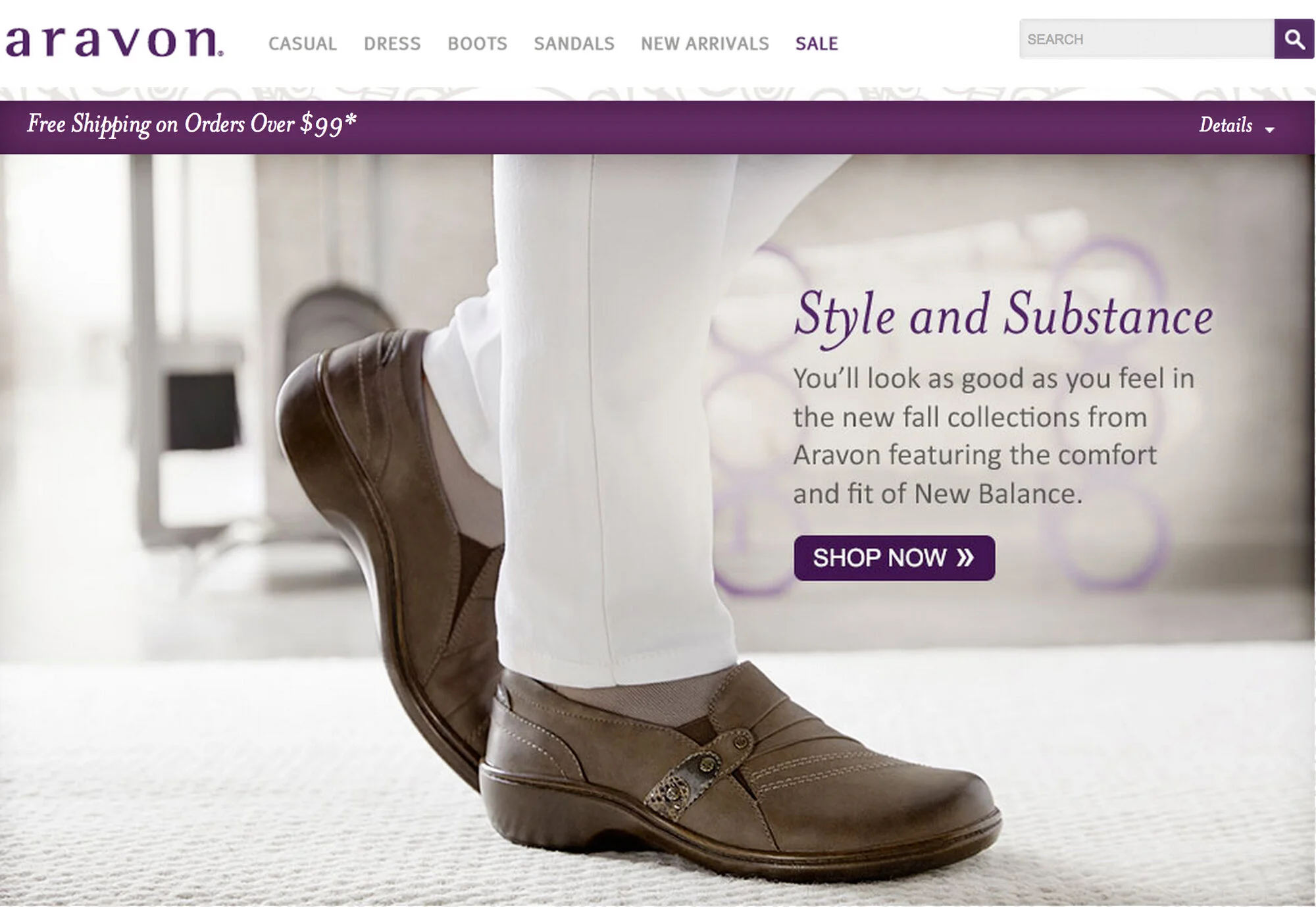 A person wearing brown New Balance shoes, white pants, and beige socks. The background includes a blurred room with light colors and some furniture. The website promotes fall collection footwear.