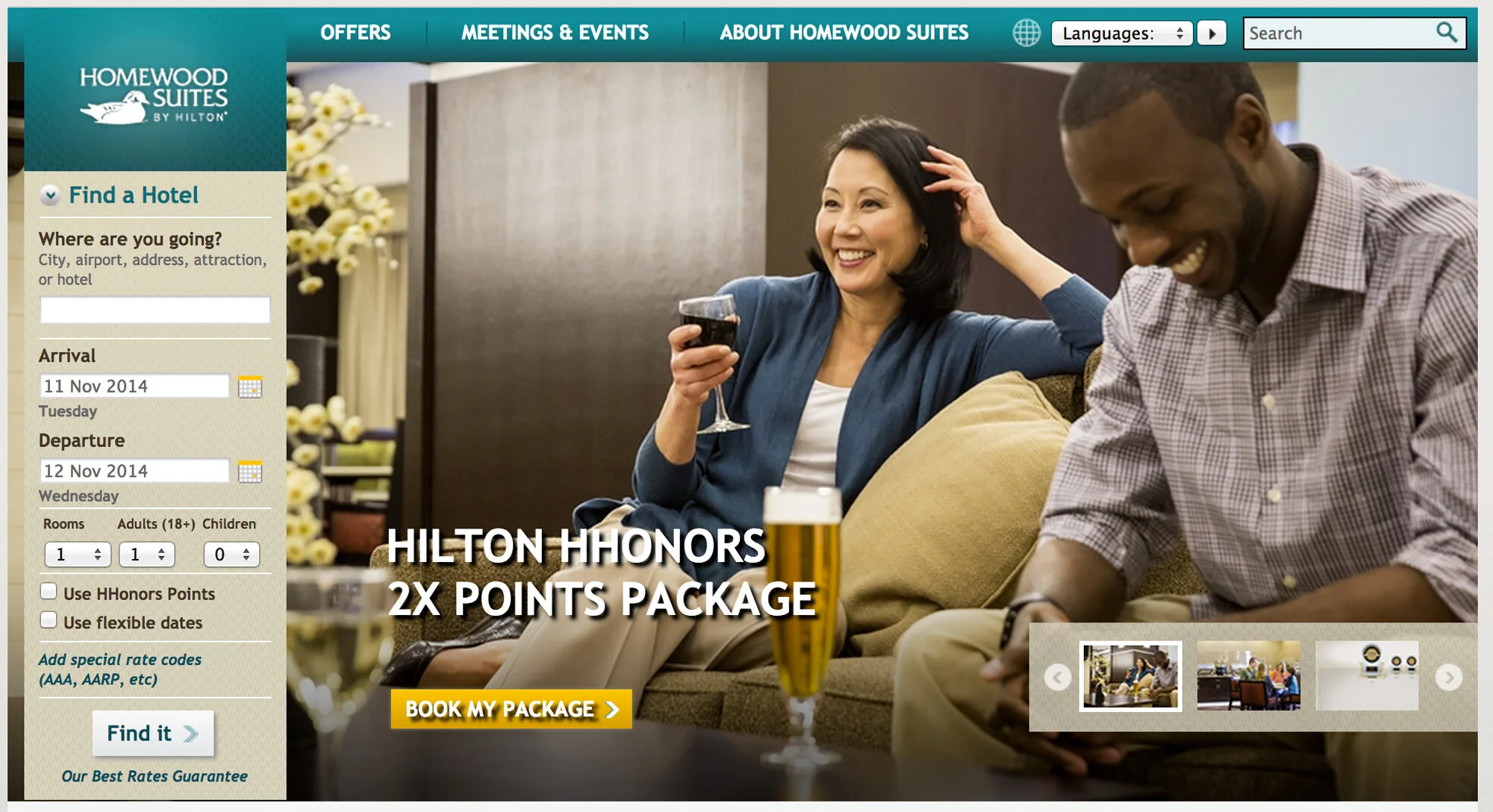 A promotional webpage for Homewood Suites by Hilton showing a smiling woman with dark hair, holding a glass of red wine, seated on a couch with a man who is looking down and smiling. There are drinks on the coffee table and a background of a hotel lo
