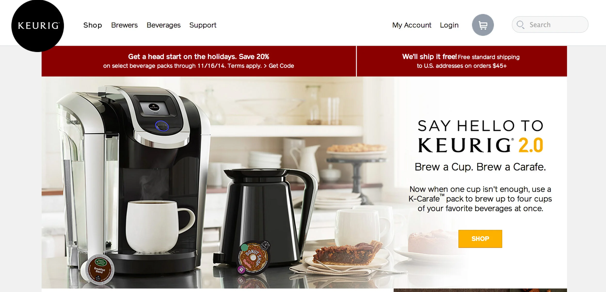 Keurig 2.0 coffee maker on a kitchen countertop with a white mug, a black kettle, and plate of coffee cake in a bright kitchen with white shelves and dishes in the background. Screenshot of a Keurig web page