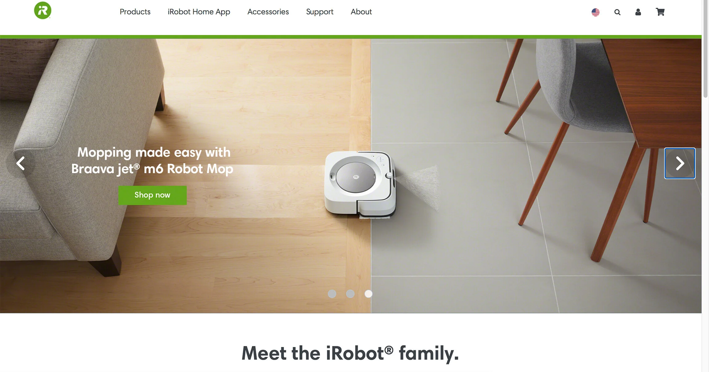 A robotic vacuum cleaner on a floor, half on light wood flooring and half on gray tile, with a sofa and dining table nearby.