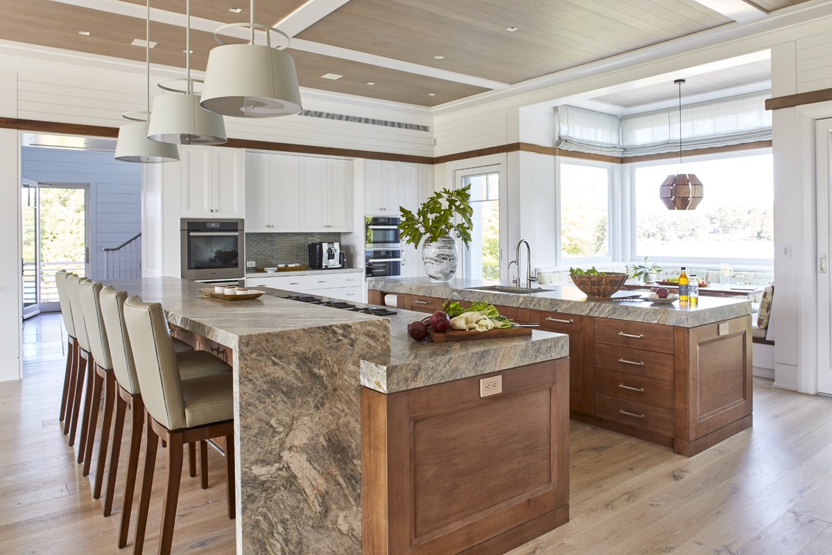 Modern kitchen with white cabinets, granite countertops, a large island, and natural light coming through bay windows.